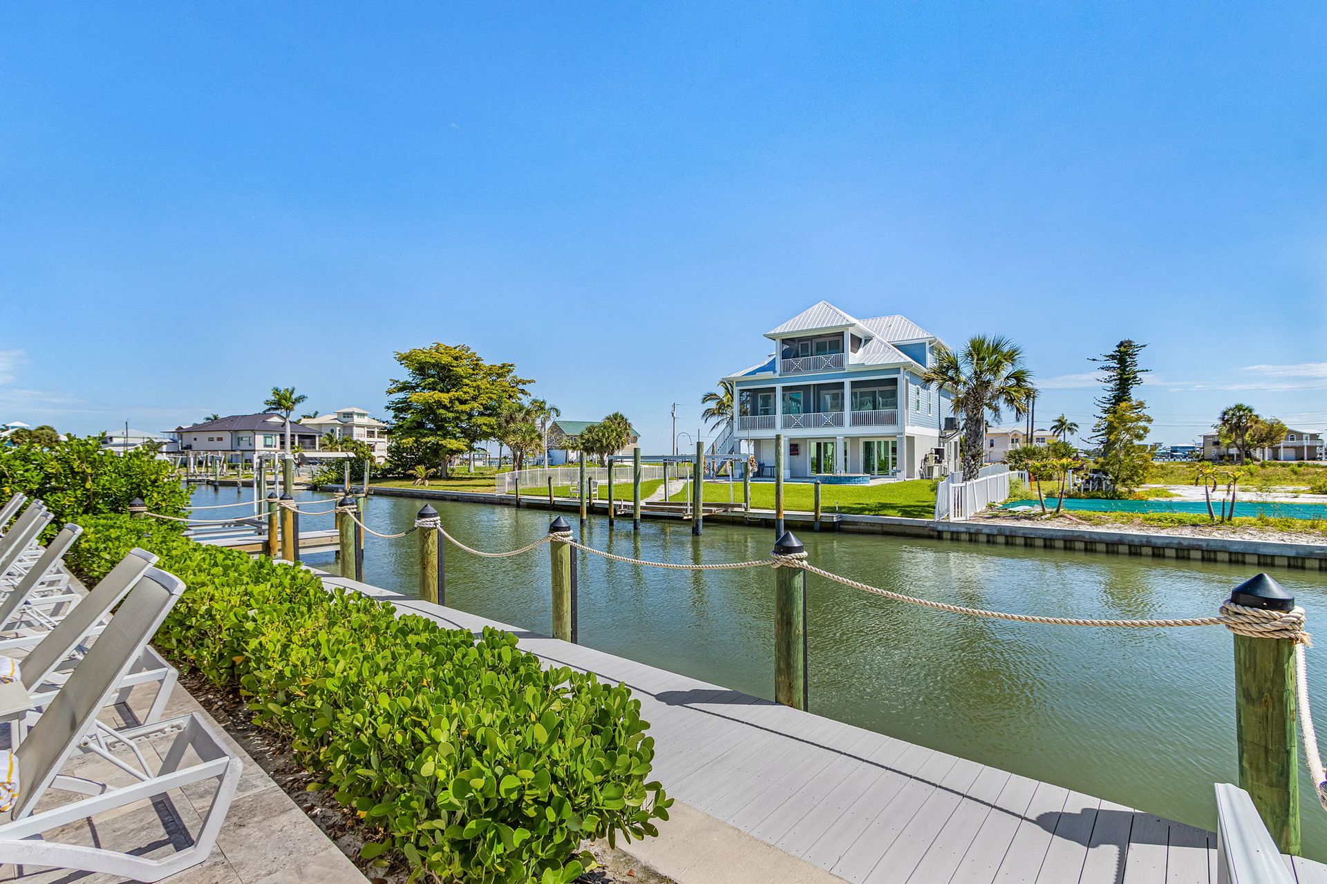 Waterfront house with dock and calm canal under a bright blue sky