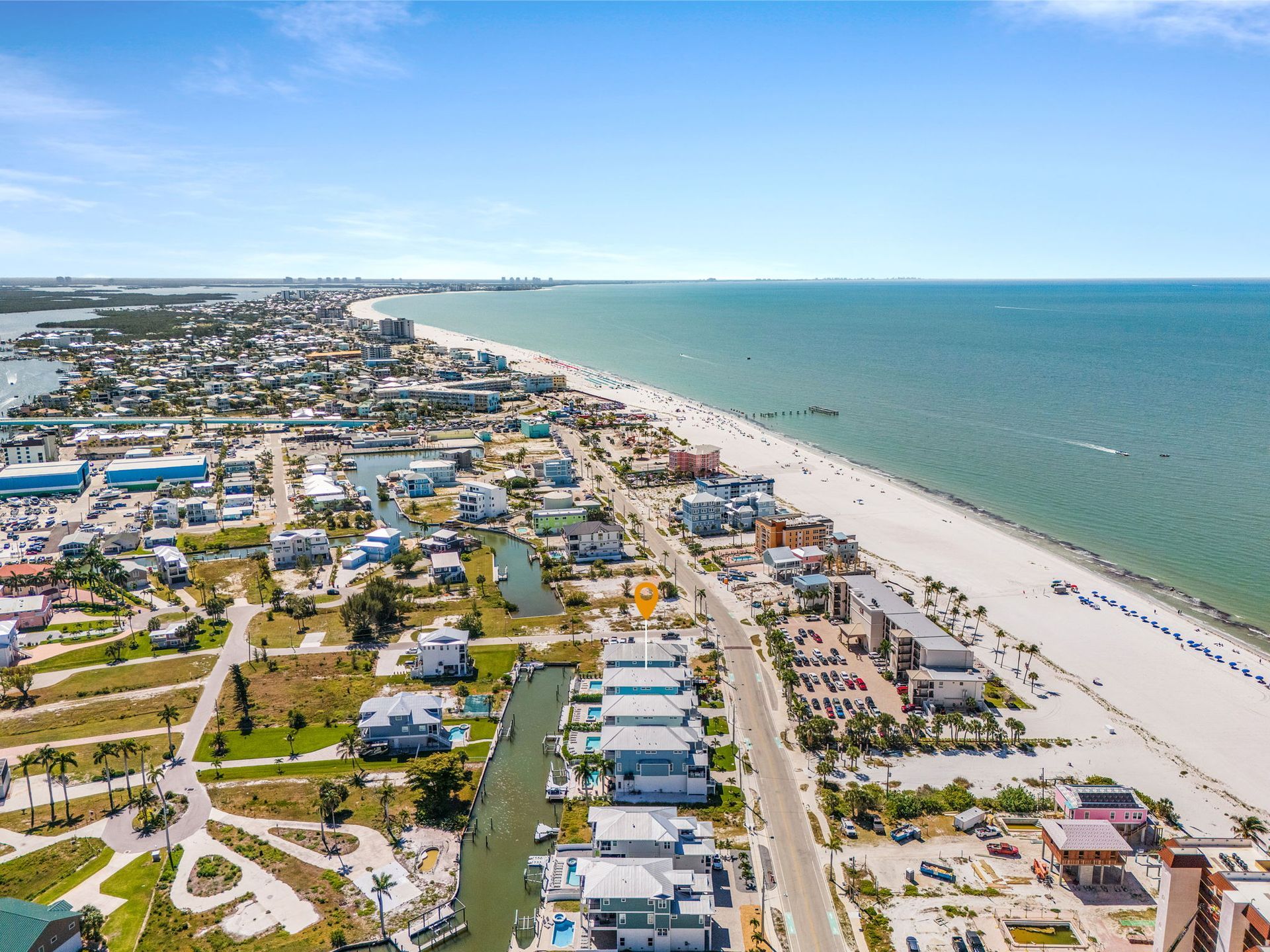 Aerial view of a coastal town with beach, turquoise ocean, and rows of colorful buildings along the shoreline