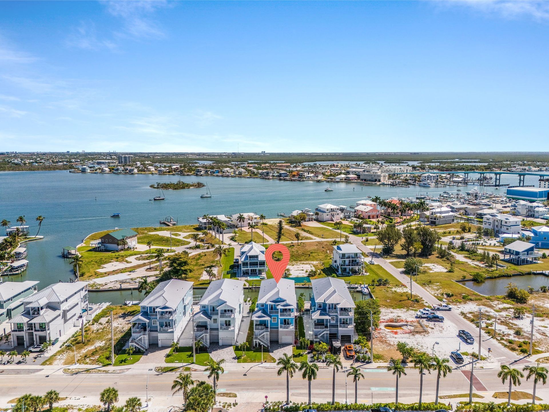 Aerial view of waterfront homes, marina, and palm-lined streets under a clear blue sky