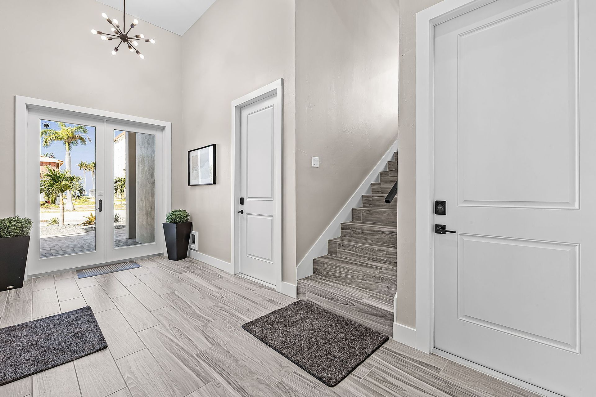 Bright entryway with white doors, carpeted stairs, and light wood floors leading to a glass front door.