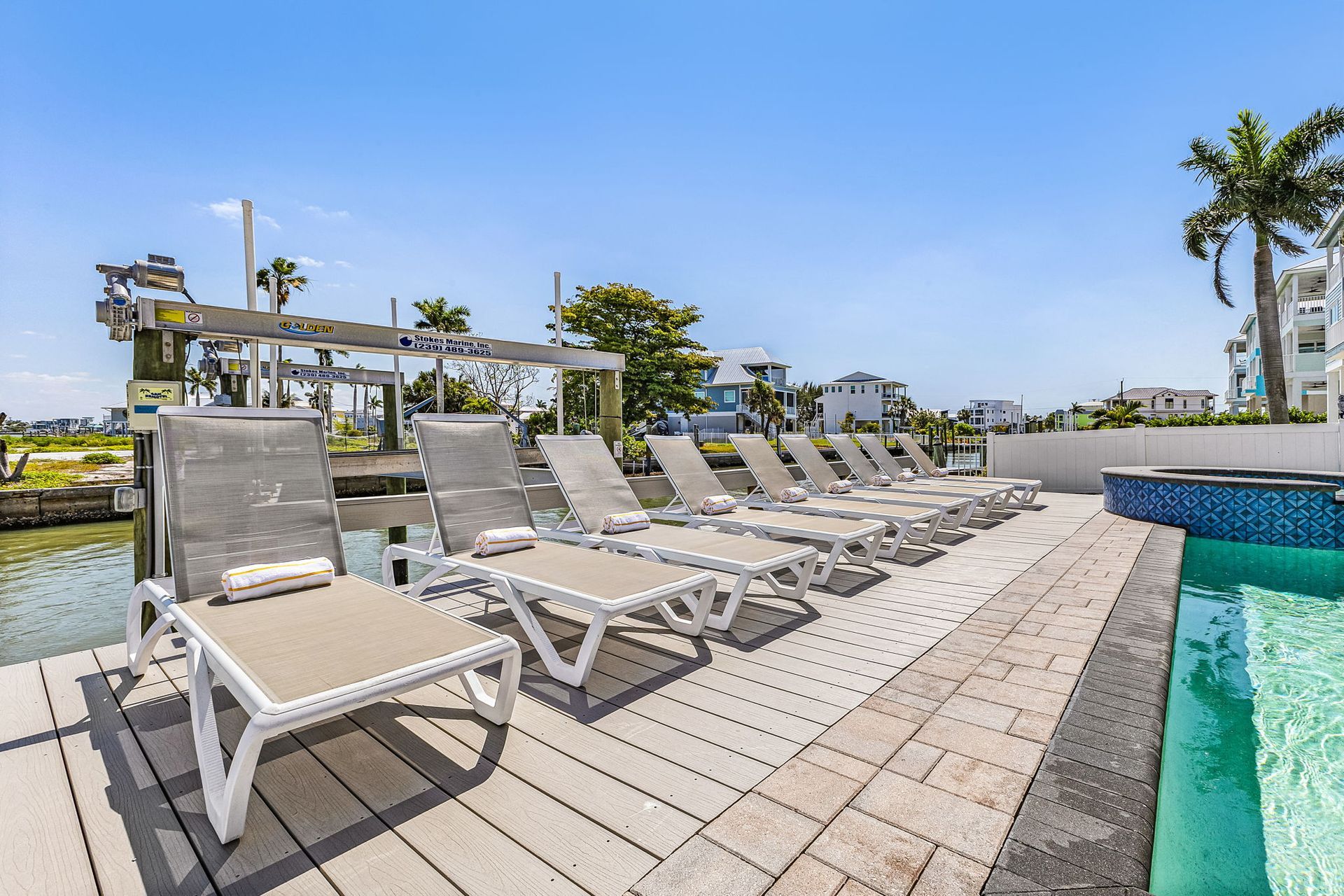Poolside lounge chairs beside a turquoise pool under a sunny sky