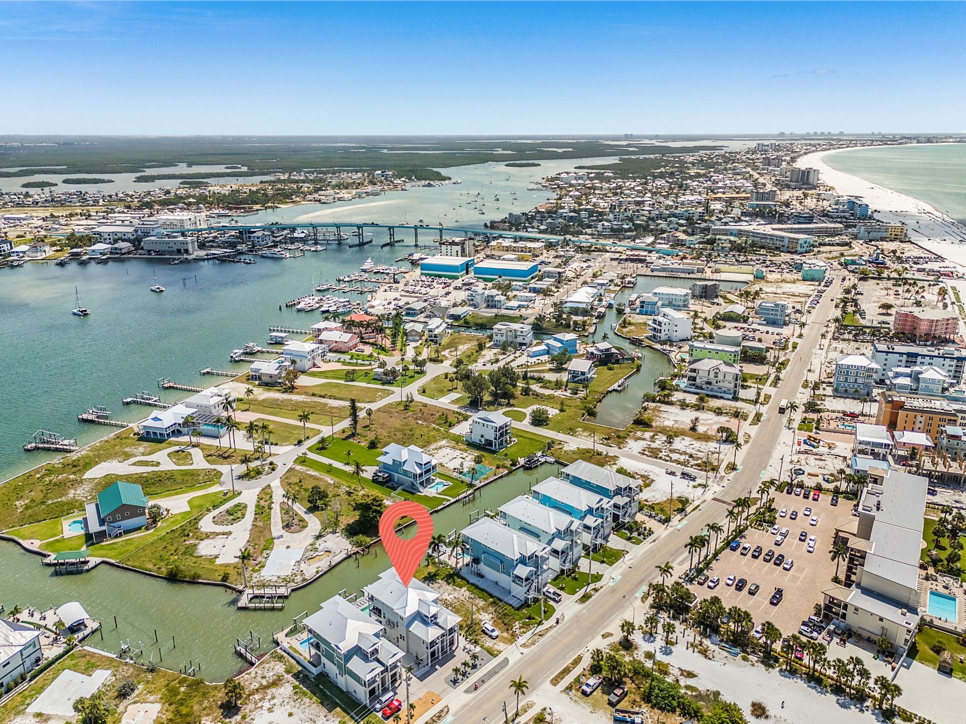 Aerial view of a coastal marina and waterfront neighborhood with boats, roads, and sandy beach.