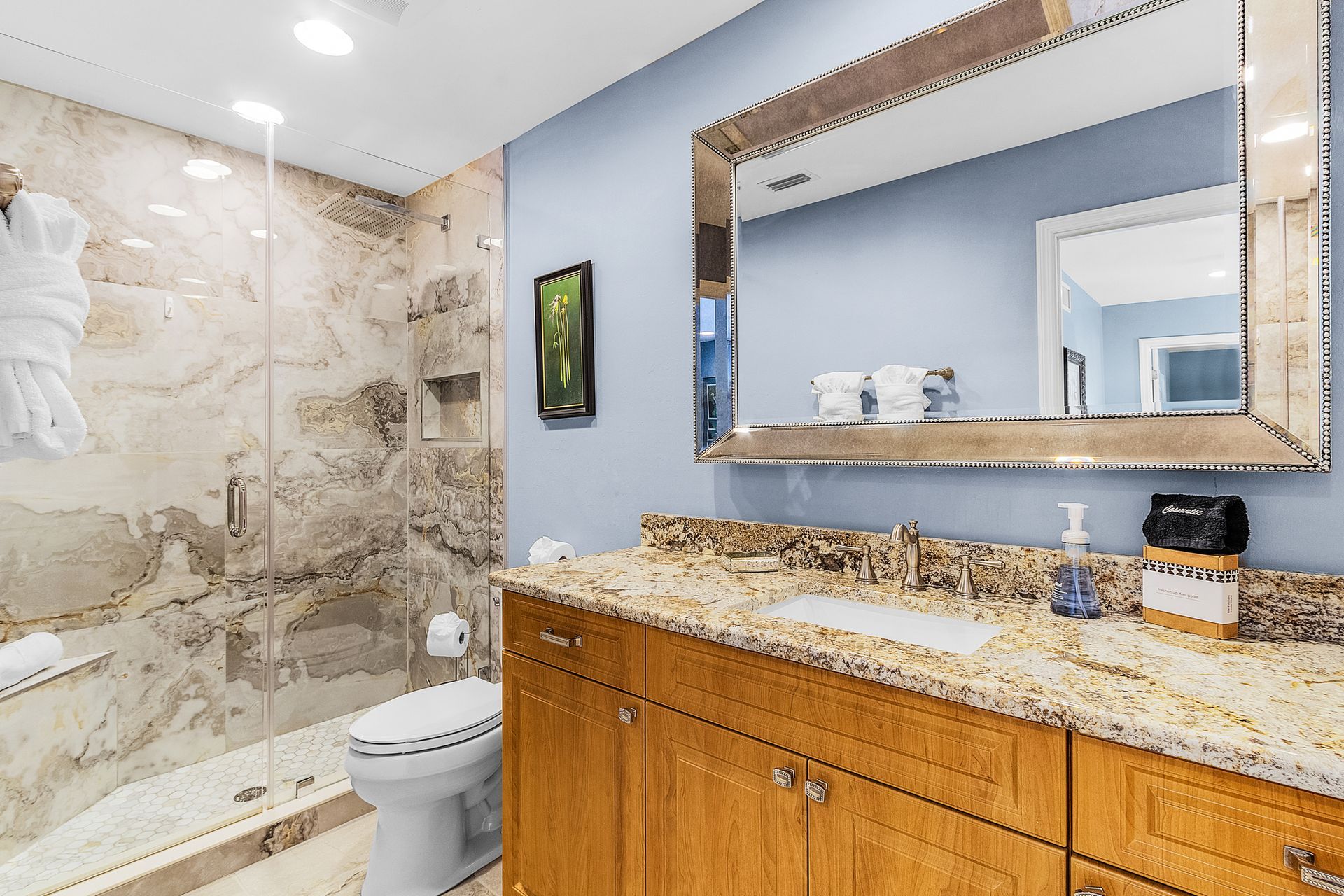 Modern bathroom with granite vanity, large mirror, marble-tile shower, and toilet