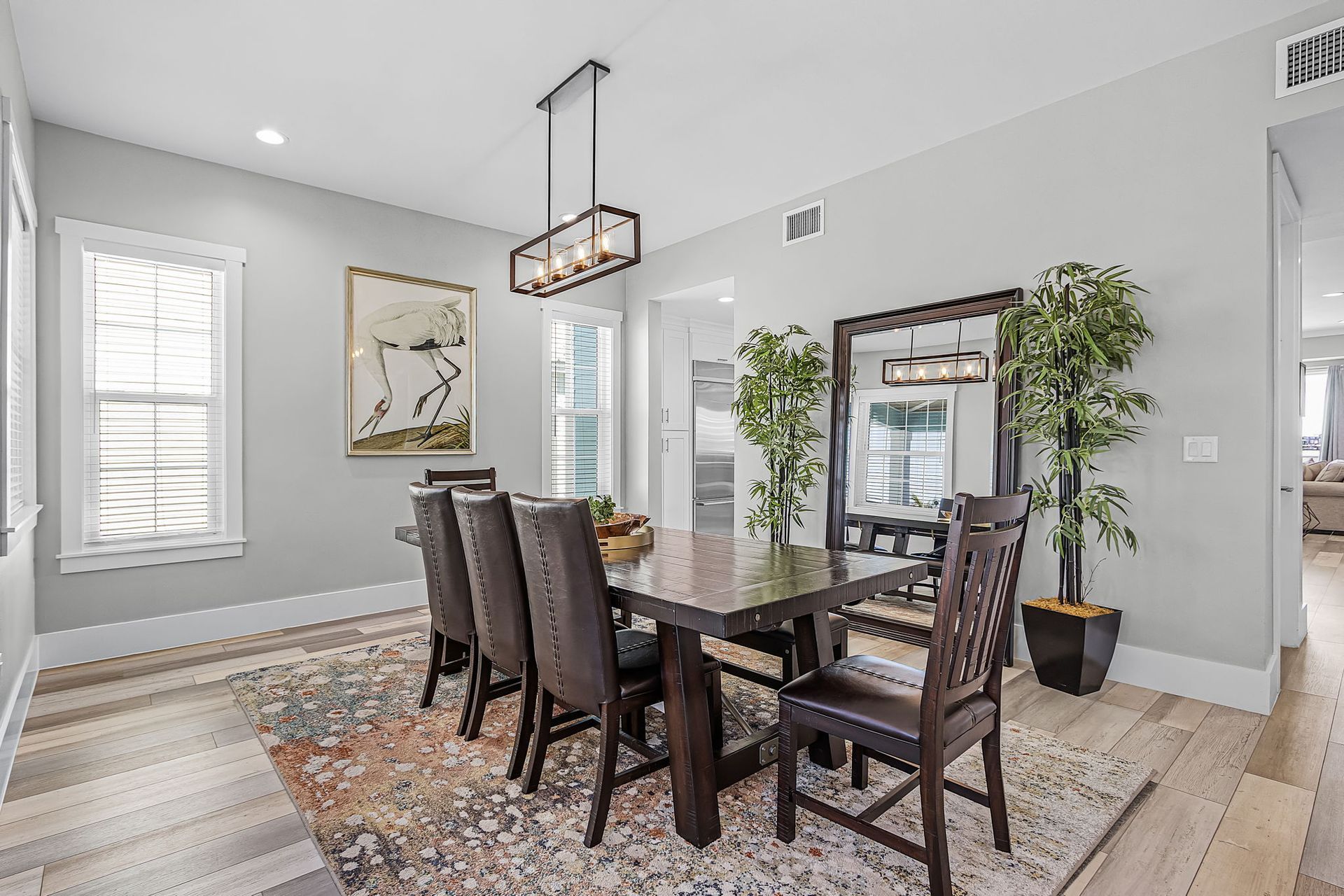 Bright dining room with dark wood table, chairs, rug, gray walls, and large windows