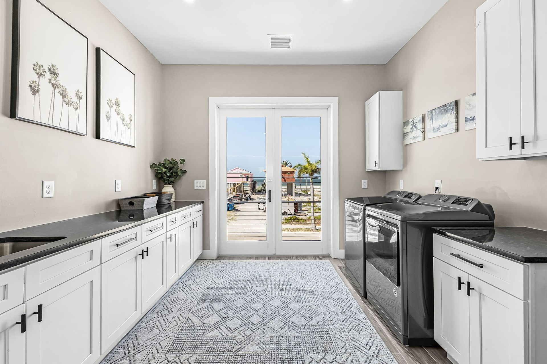 Bright white kitchen with gray rug, stainless stove, and glass doors opening to a patio view