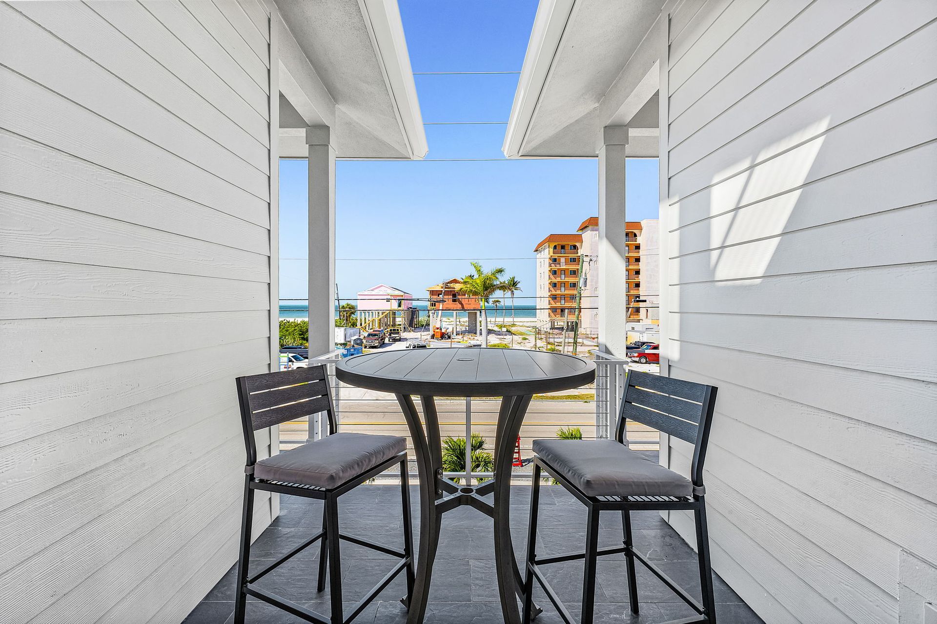 Balcony seating with round table and two chairs overlooking a beach resort and ocean view