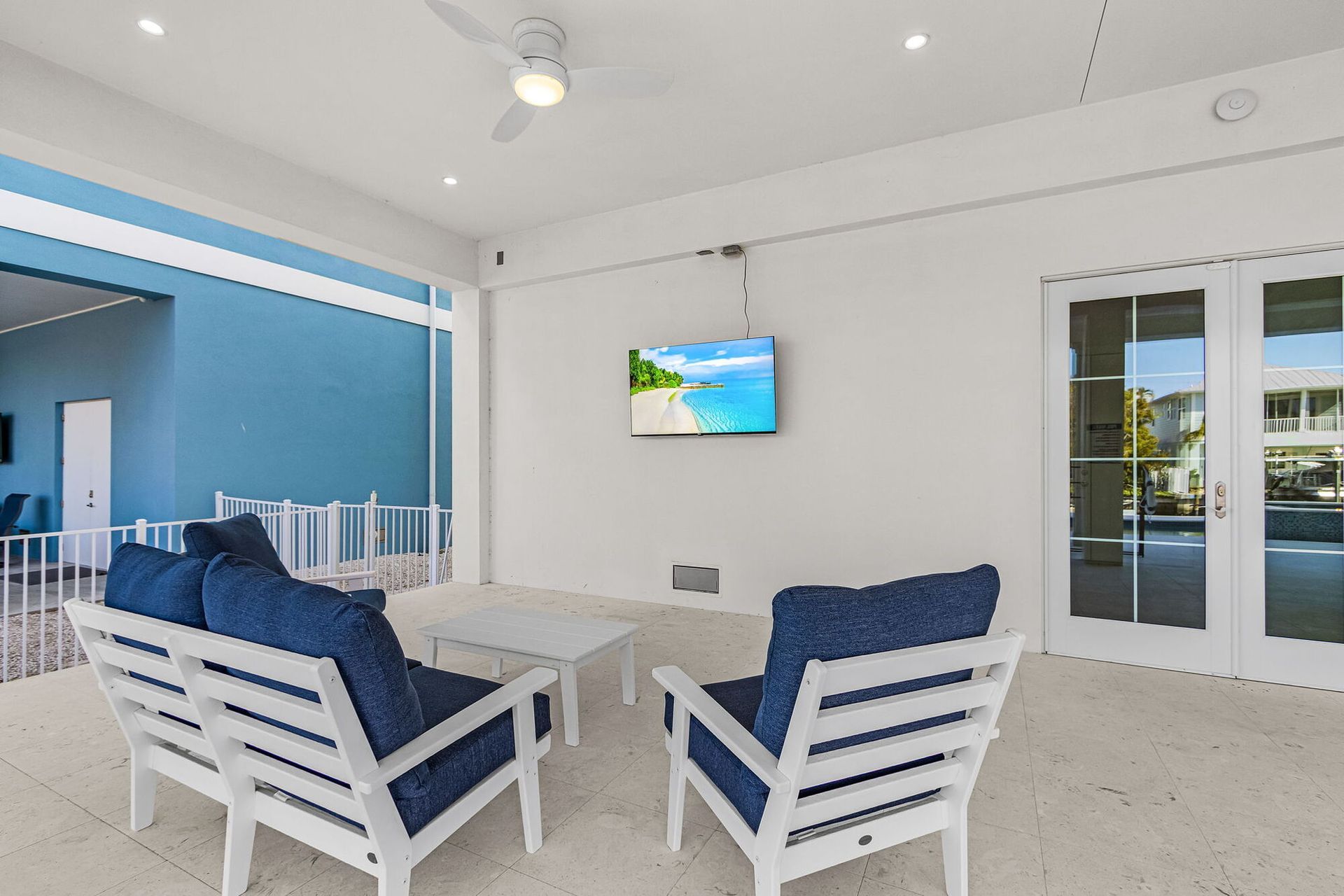 Bright living room with blue chairs, TV, and sliding glass doors to a patio