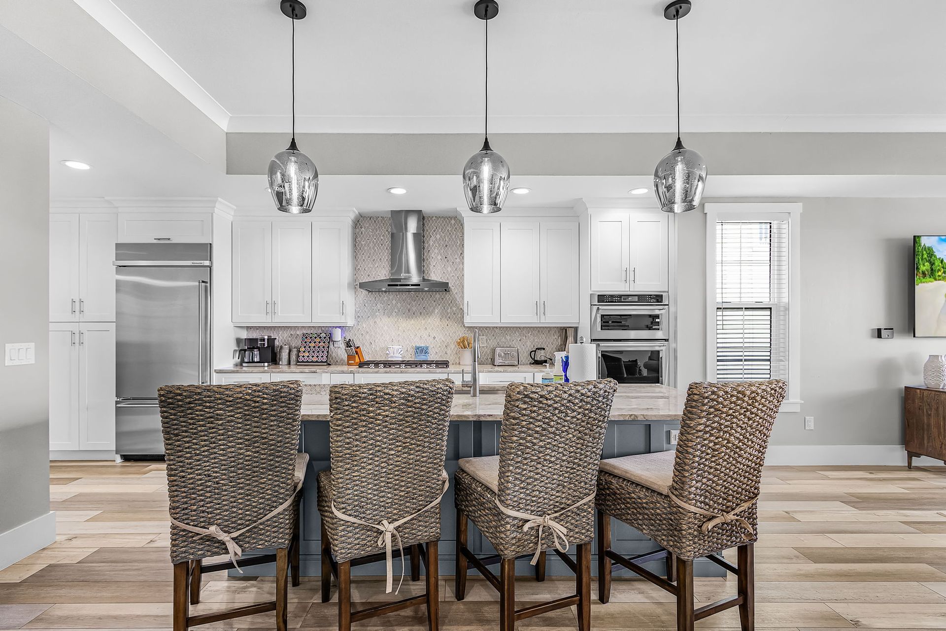 Bright modern kitchen with white cabinets, island seating, and stainless steel appliances