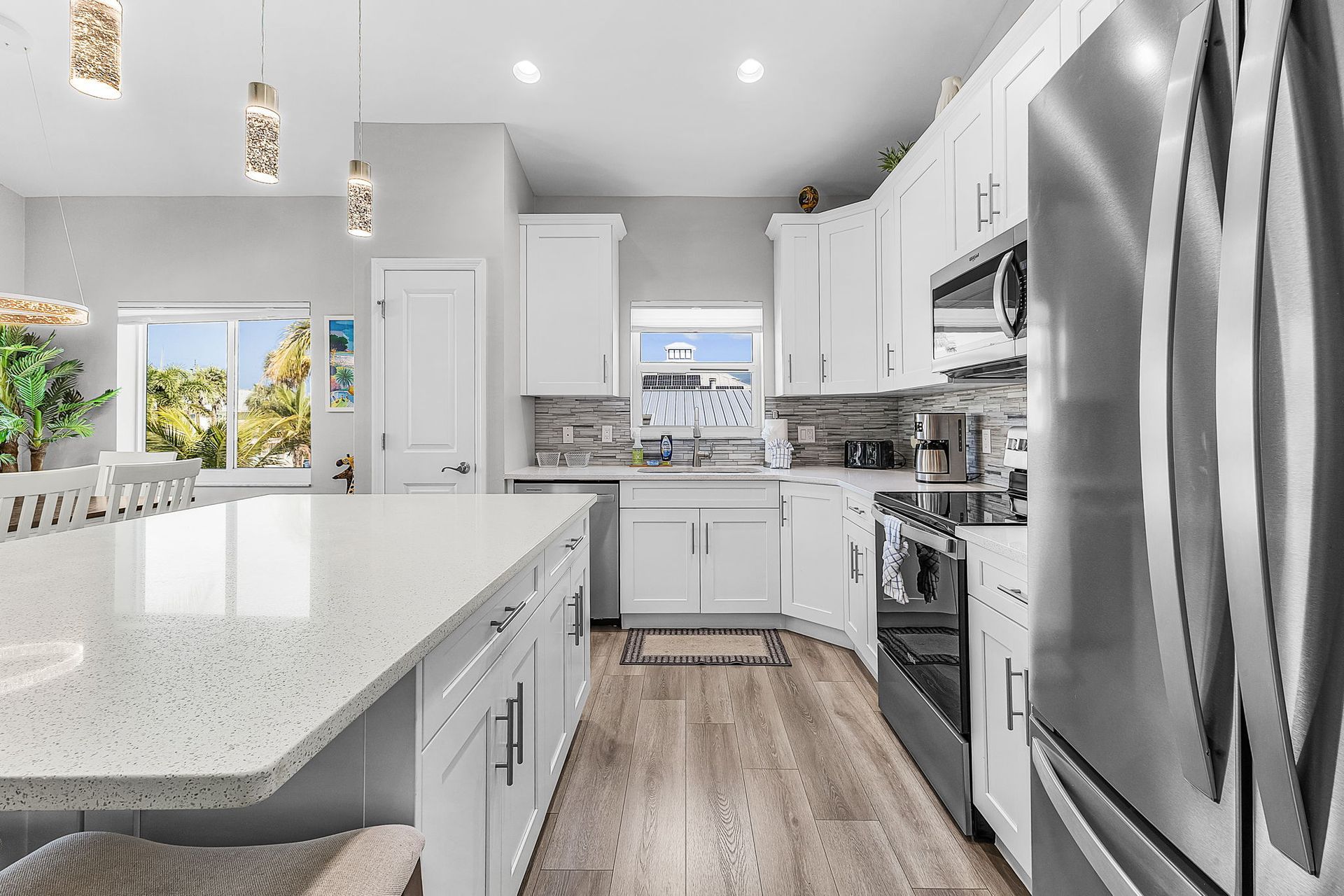 Bright modern kitchen with white cabinets, stainless appliances, and a large island