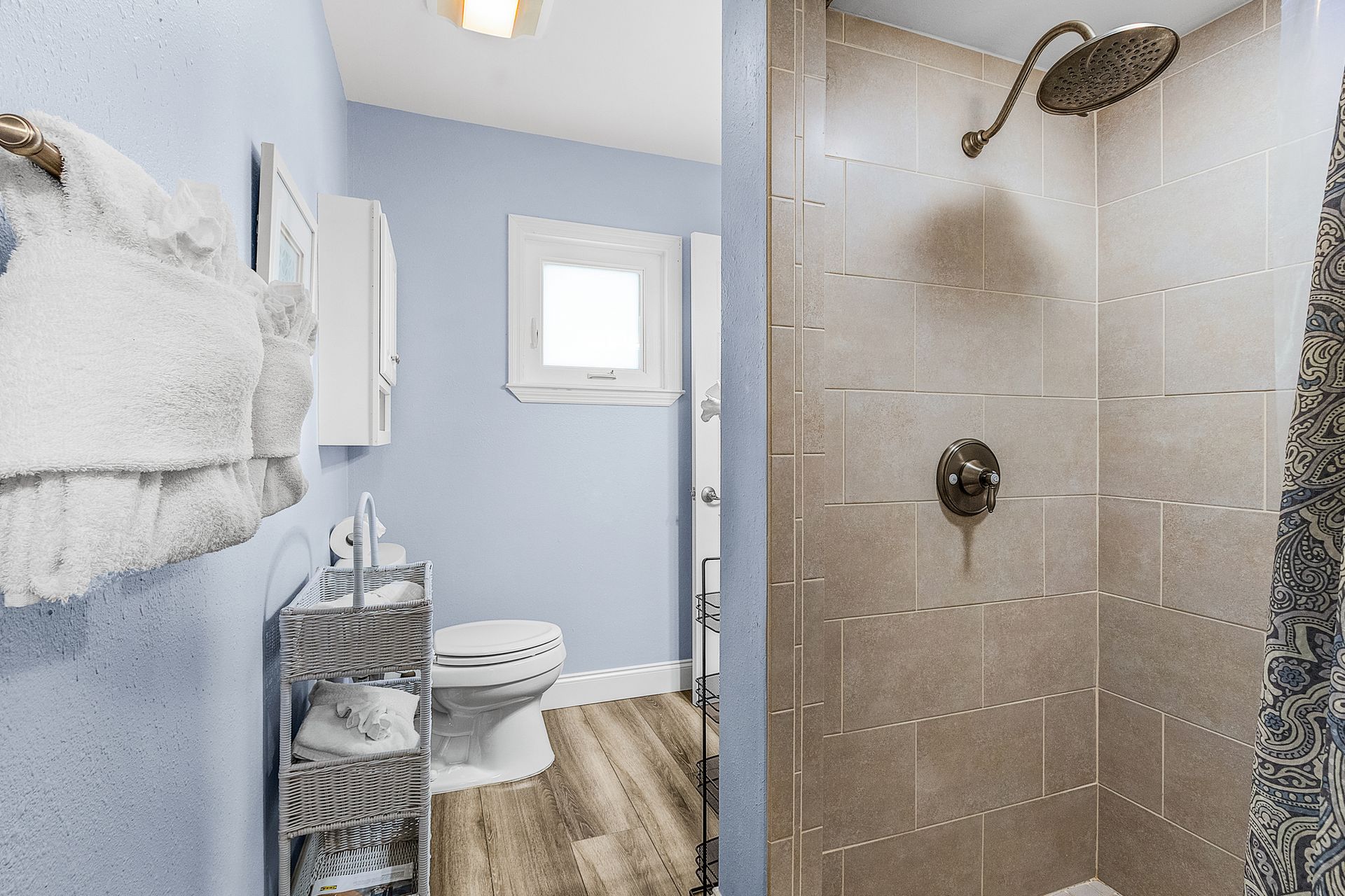 Small bathroom with shower, toilet, towel rack, and light blue walls