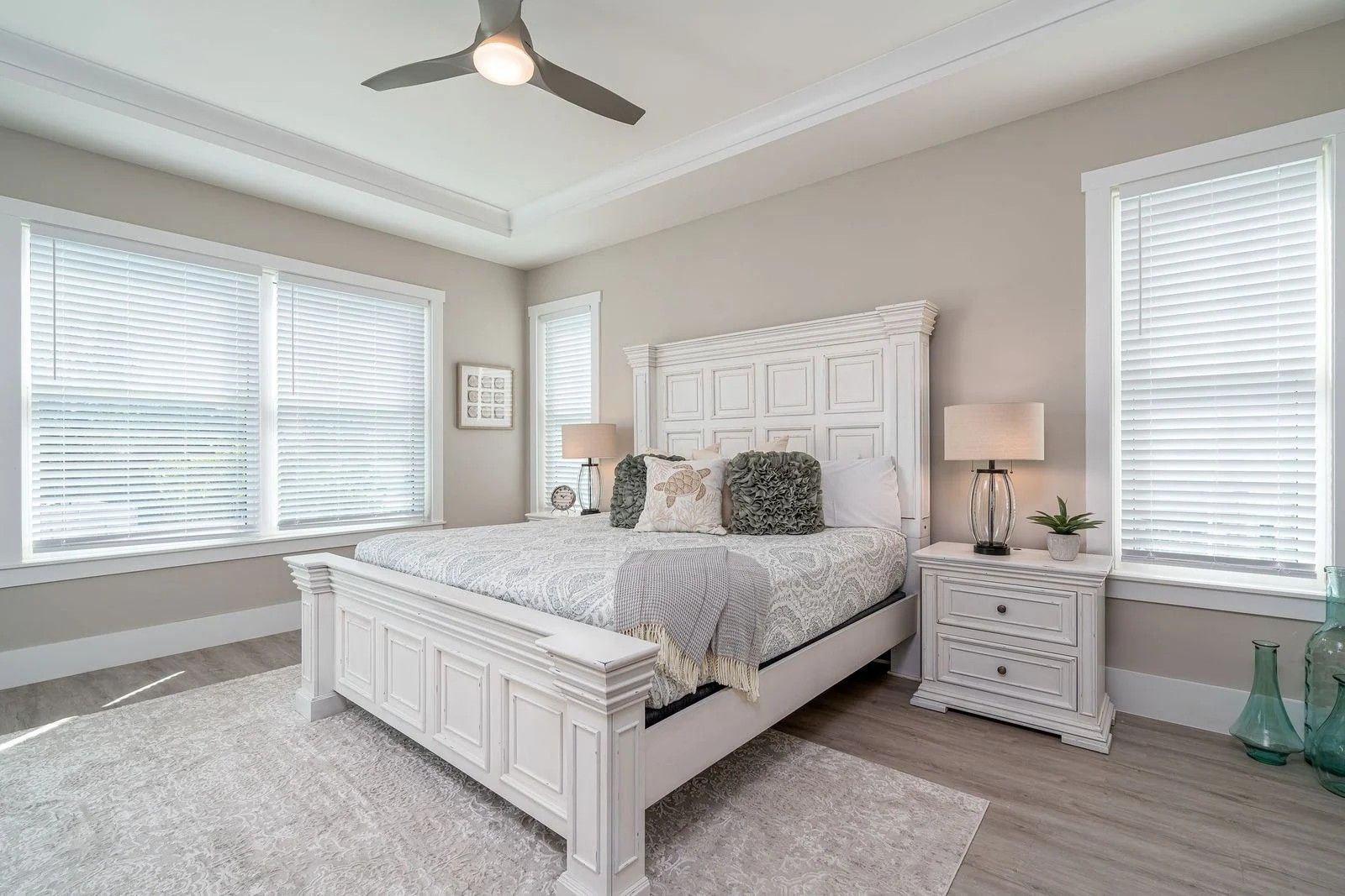 Bright modern bedroom with a white bed, nightstands, large windows, and gray carpet