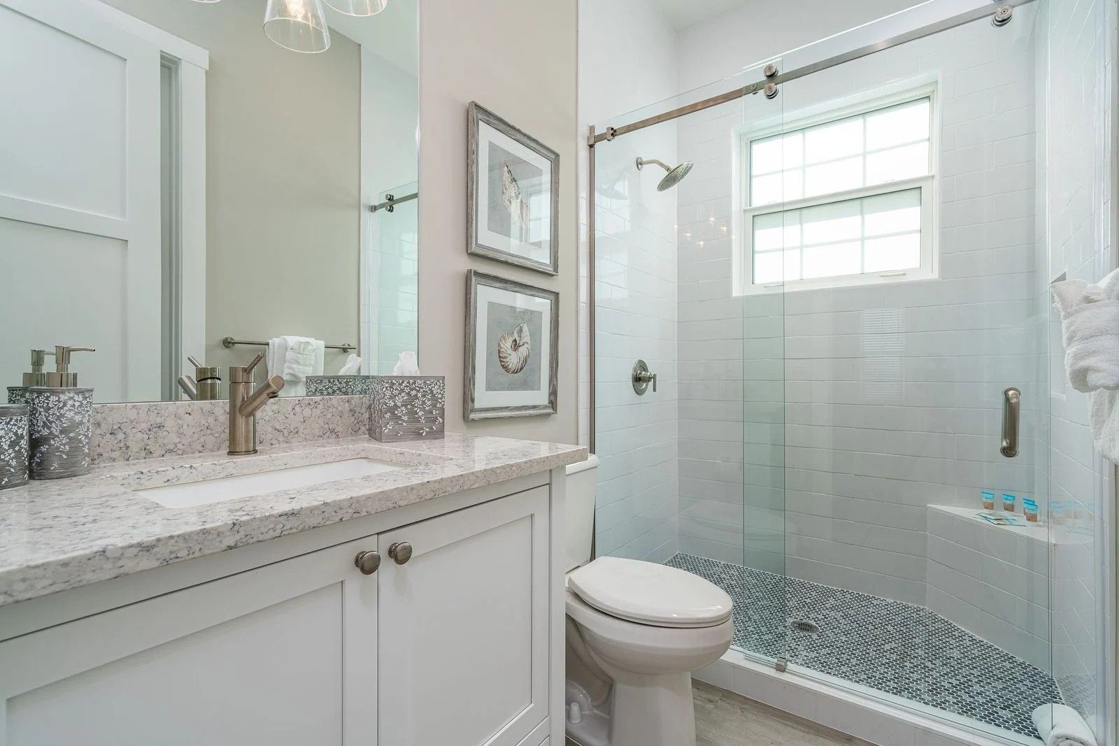 Bright white bathroom with vanity sink, framed art, and glass shower enclosure