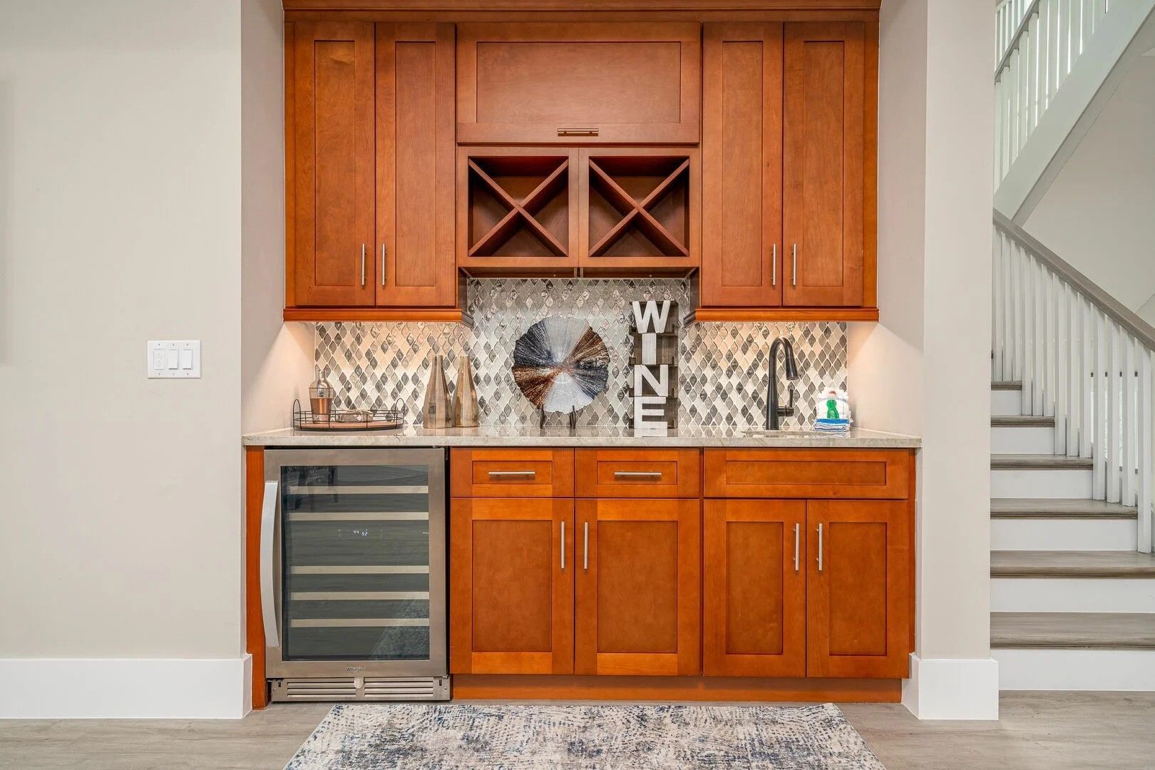 Built-in wooden wet bar with wine fridge and glass cabinets in a home hallway