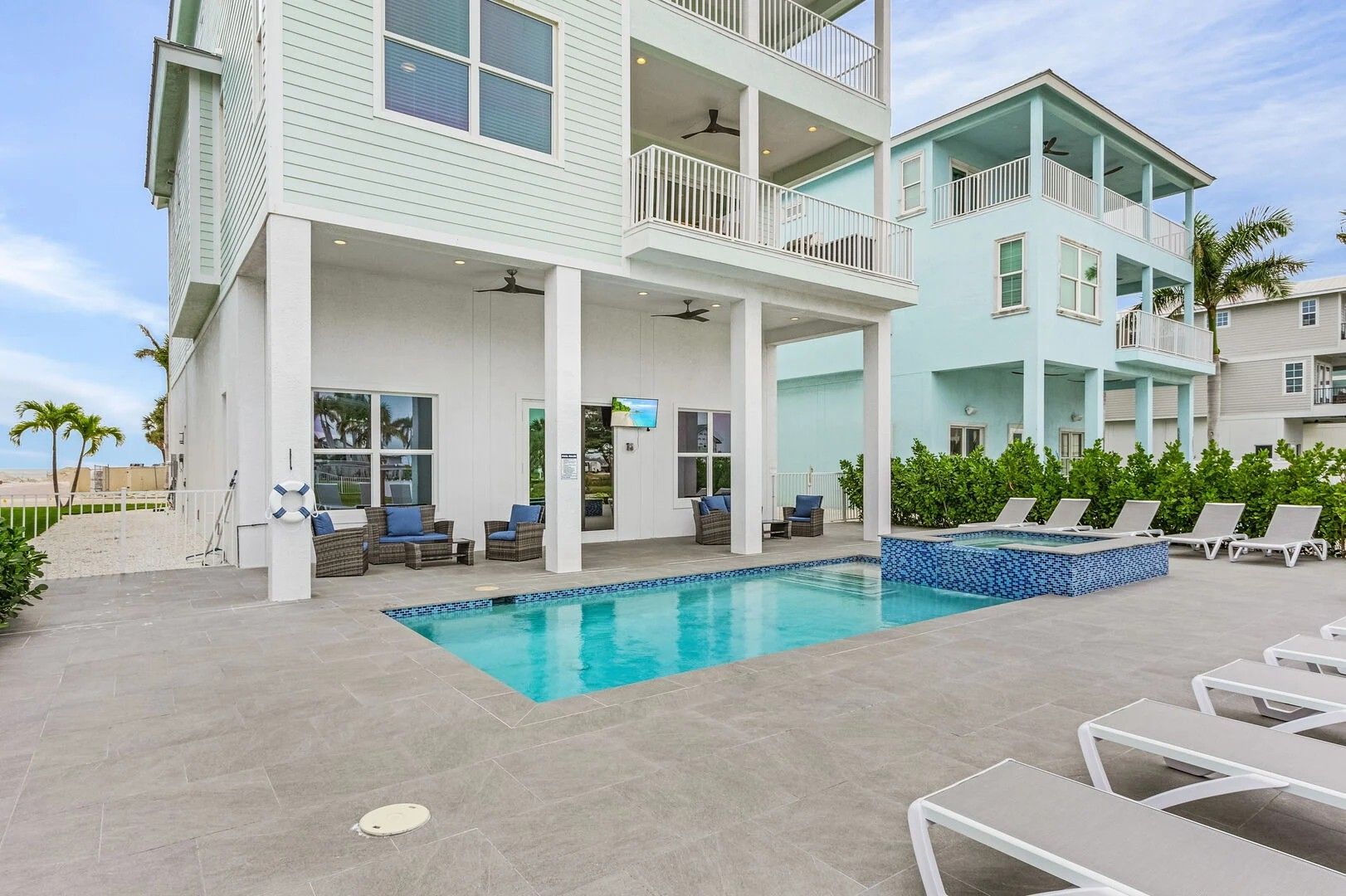 Modern beachfront condo with a small pool, lounge chairs, and ocean-view balconies