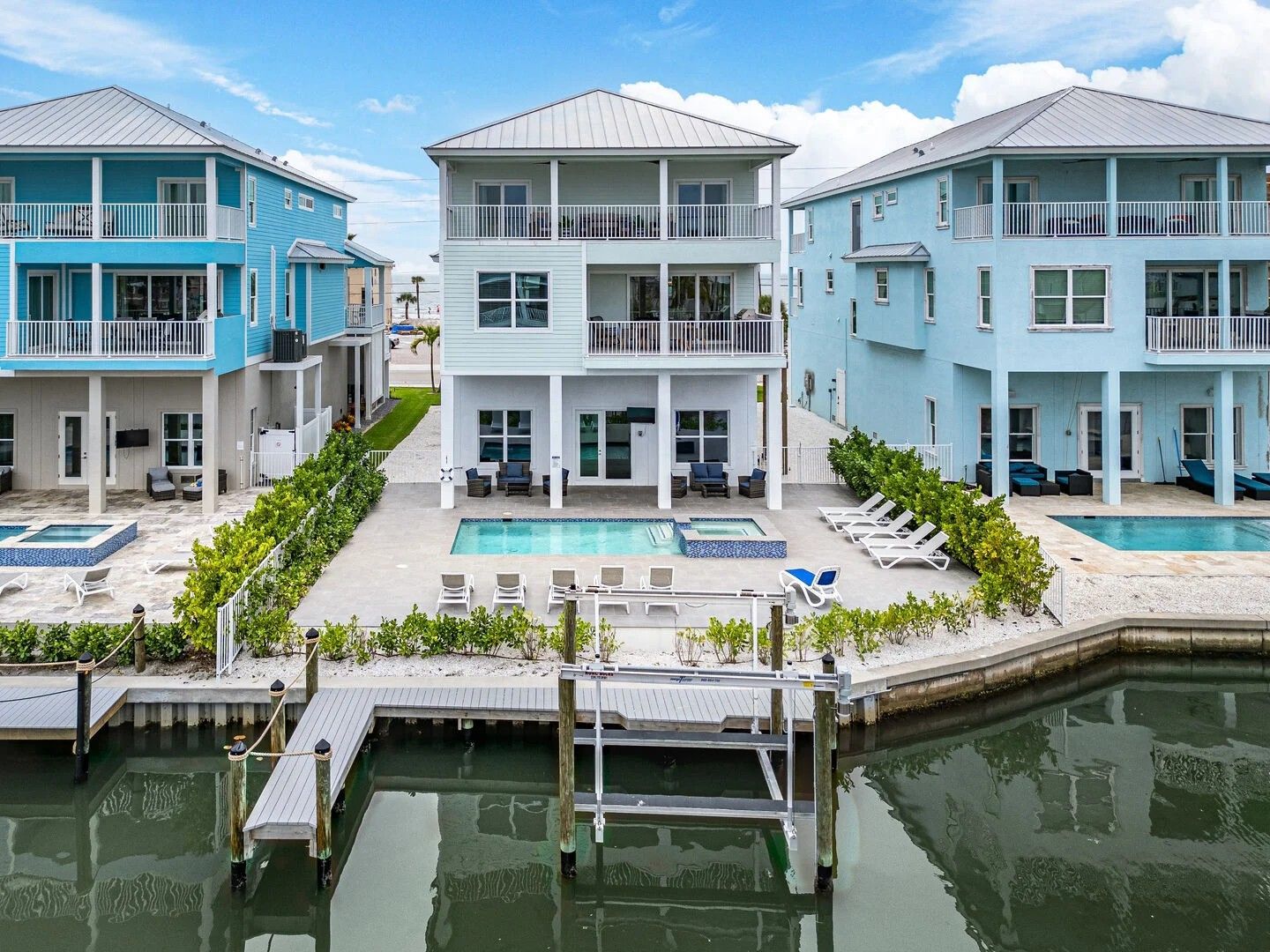Waterfront row of pastel blue beach houses with docks and patios along calm water
