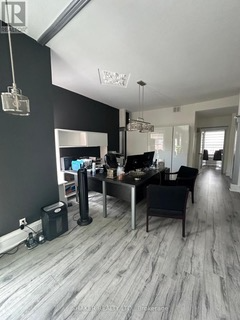 Modern office space with gray flooring, black accent wall, and a desk area with two monitors and black chairs.