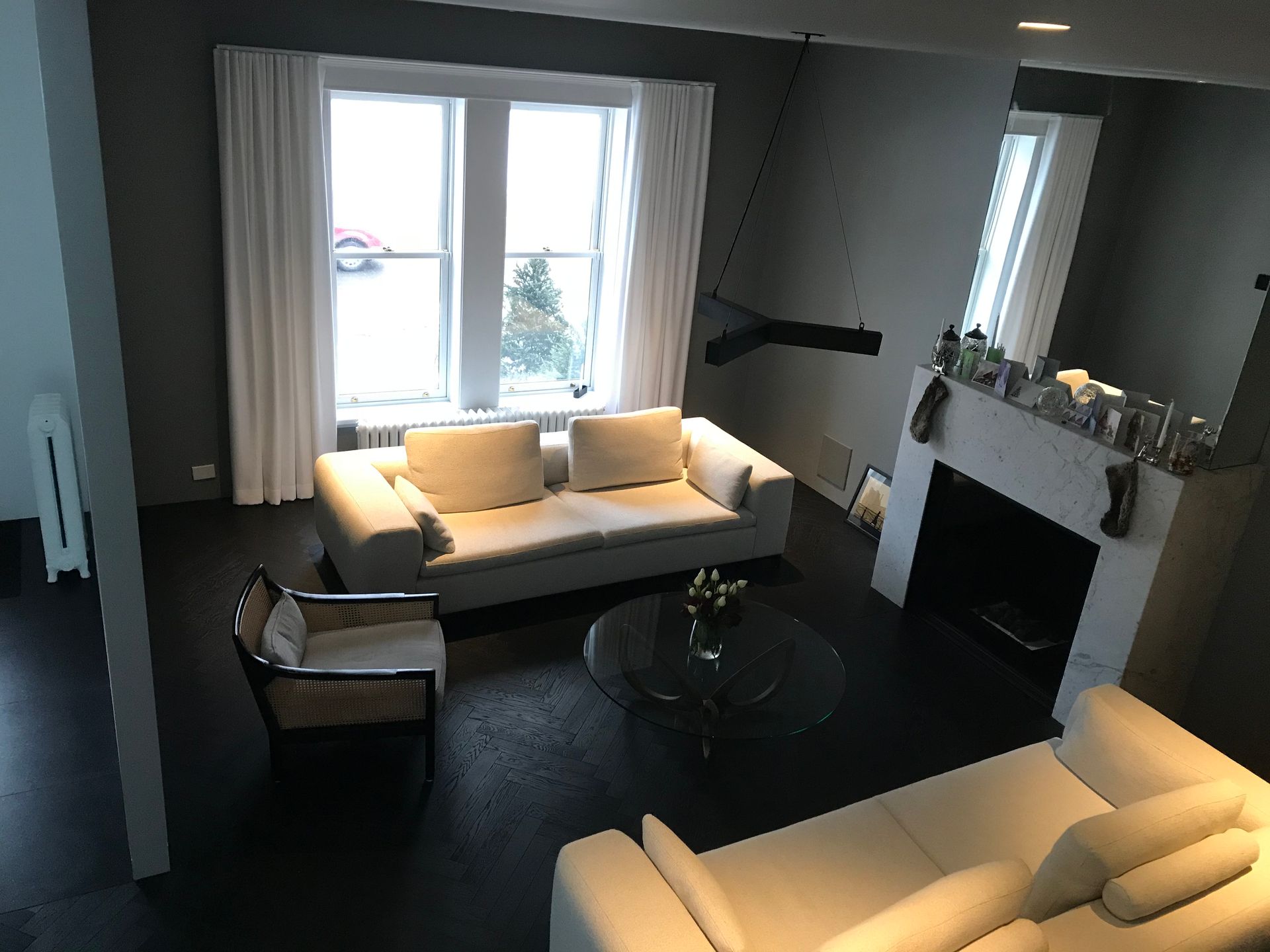 Salon moderne avec canapés blancs, moquette foncée, cheminée et fenêtres lumineuses