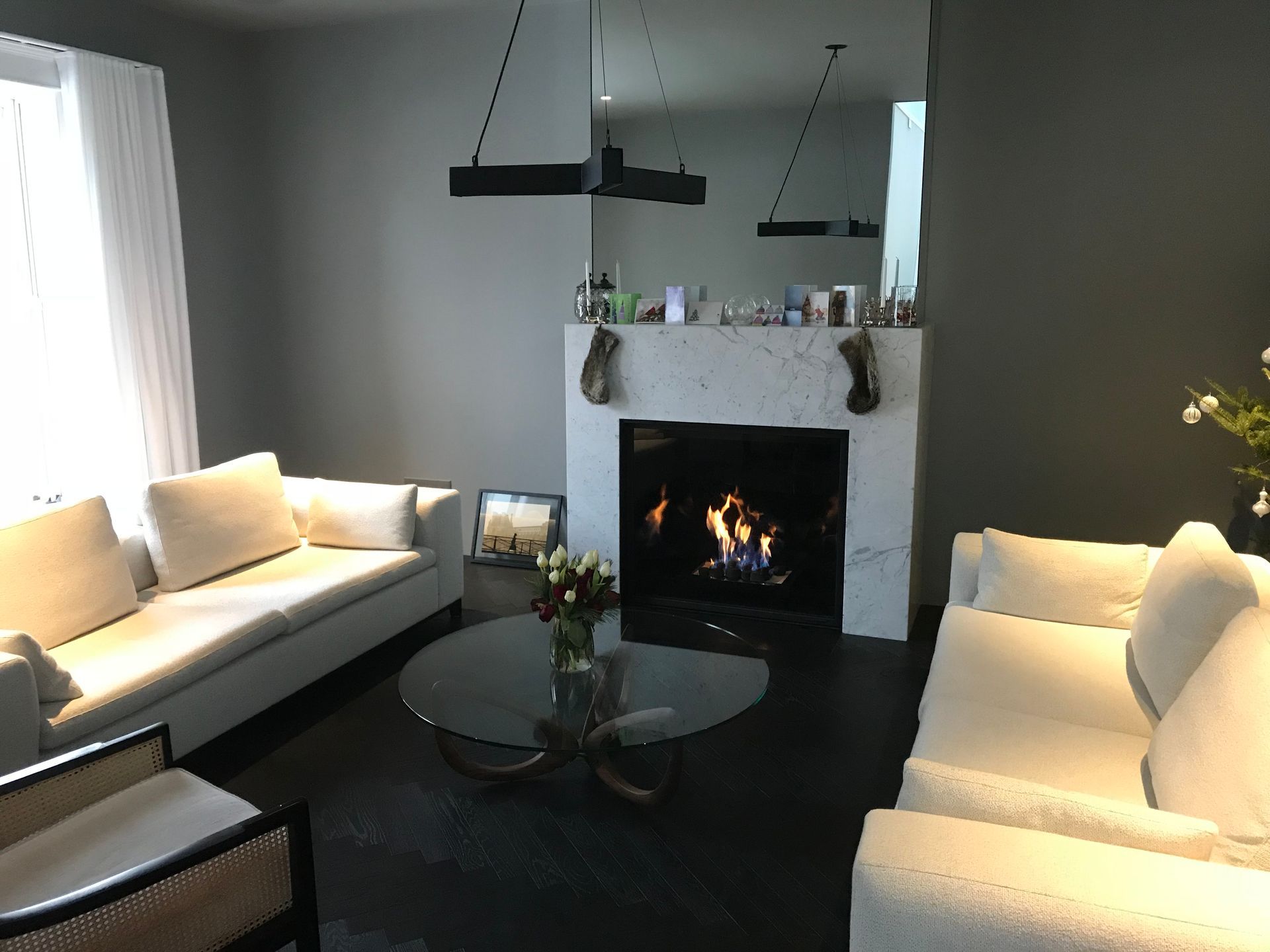 Salon moderne avec deux canapés, une table basse ronde et une cheminée allumée centrée sur un manteau blanc.