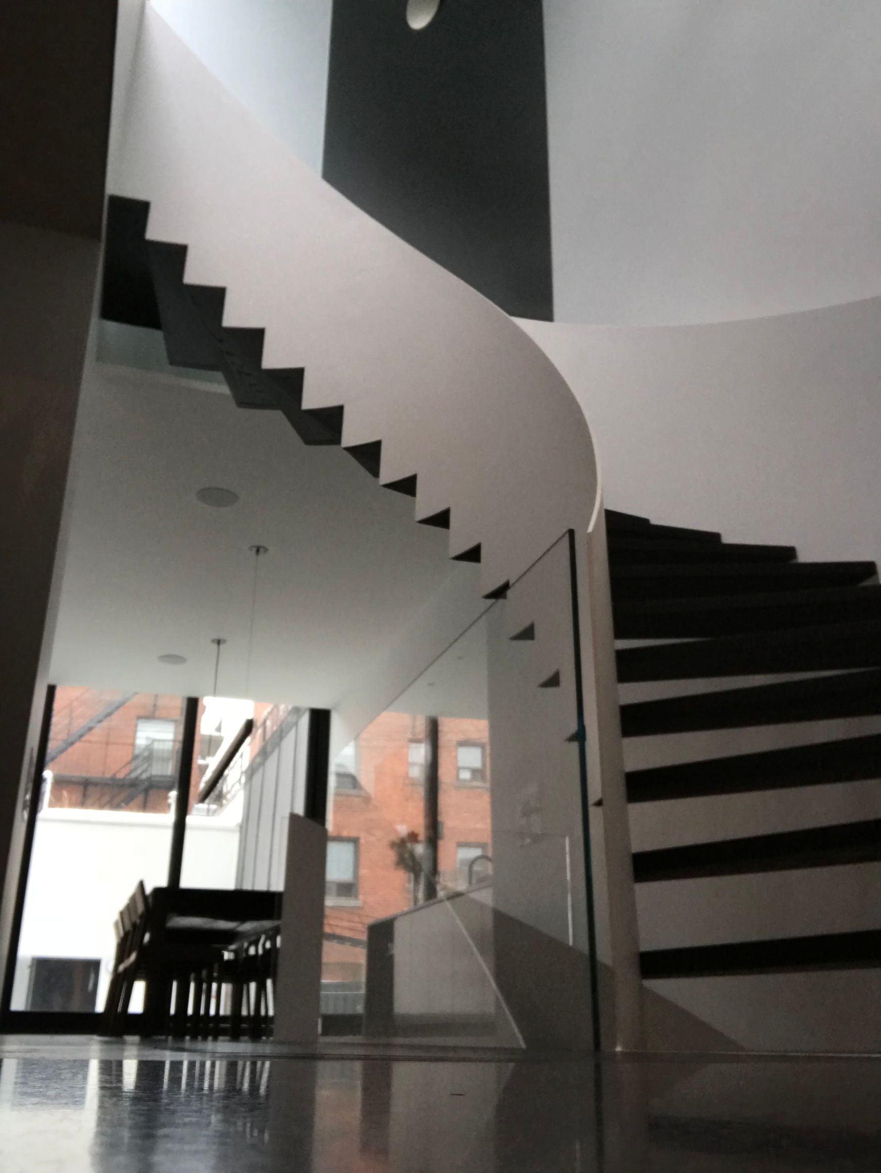 Escalier moderne dans un intérieur minimaliste lumineux avec marches noires et murs blancs incurvés