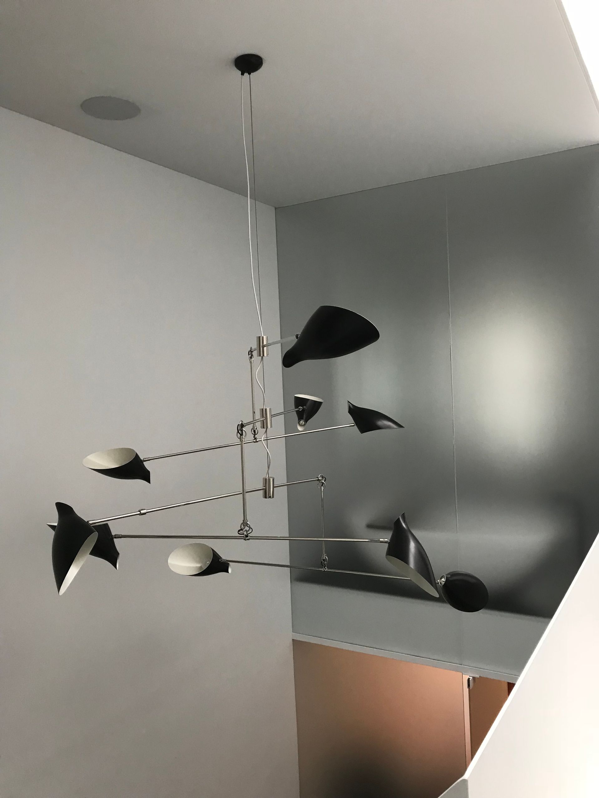 Mobile suspendu moderne avec des oiseaux noirs et des touches de blanc dans une pièce d'angle, près d'un escalier.