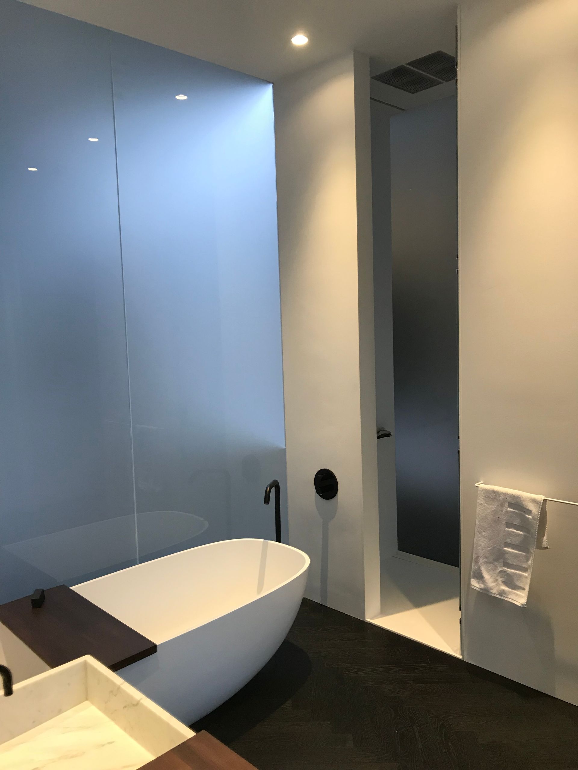 Salle de bains moderne avec baignoire îlot, mur bleu brillant et sol foncé