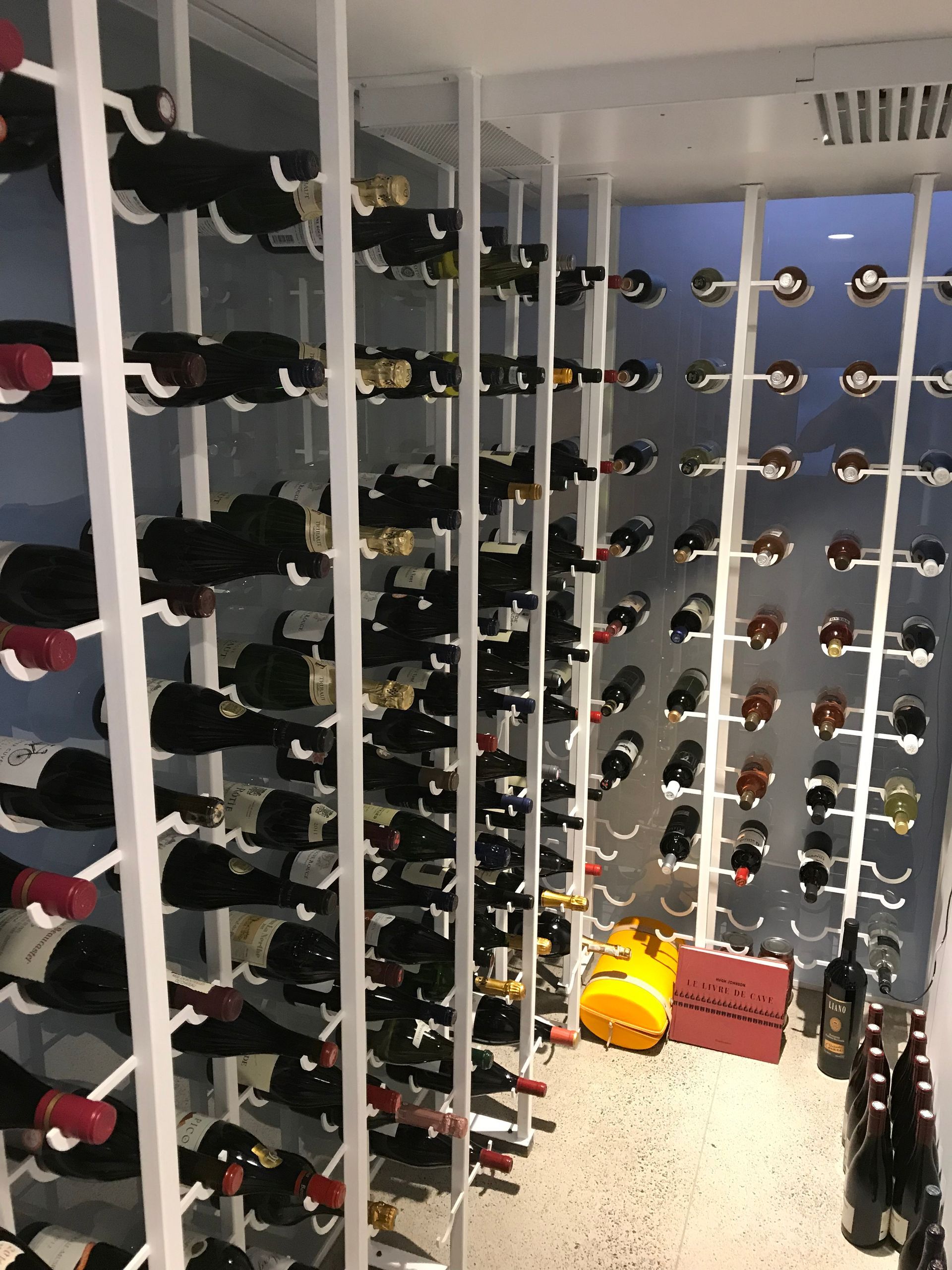Cave à vin avec des rangées de bouteilles sur des étagères murales et un mur du fond bleu