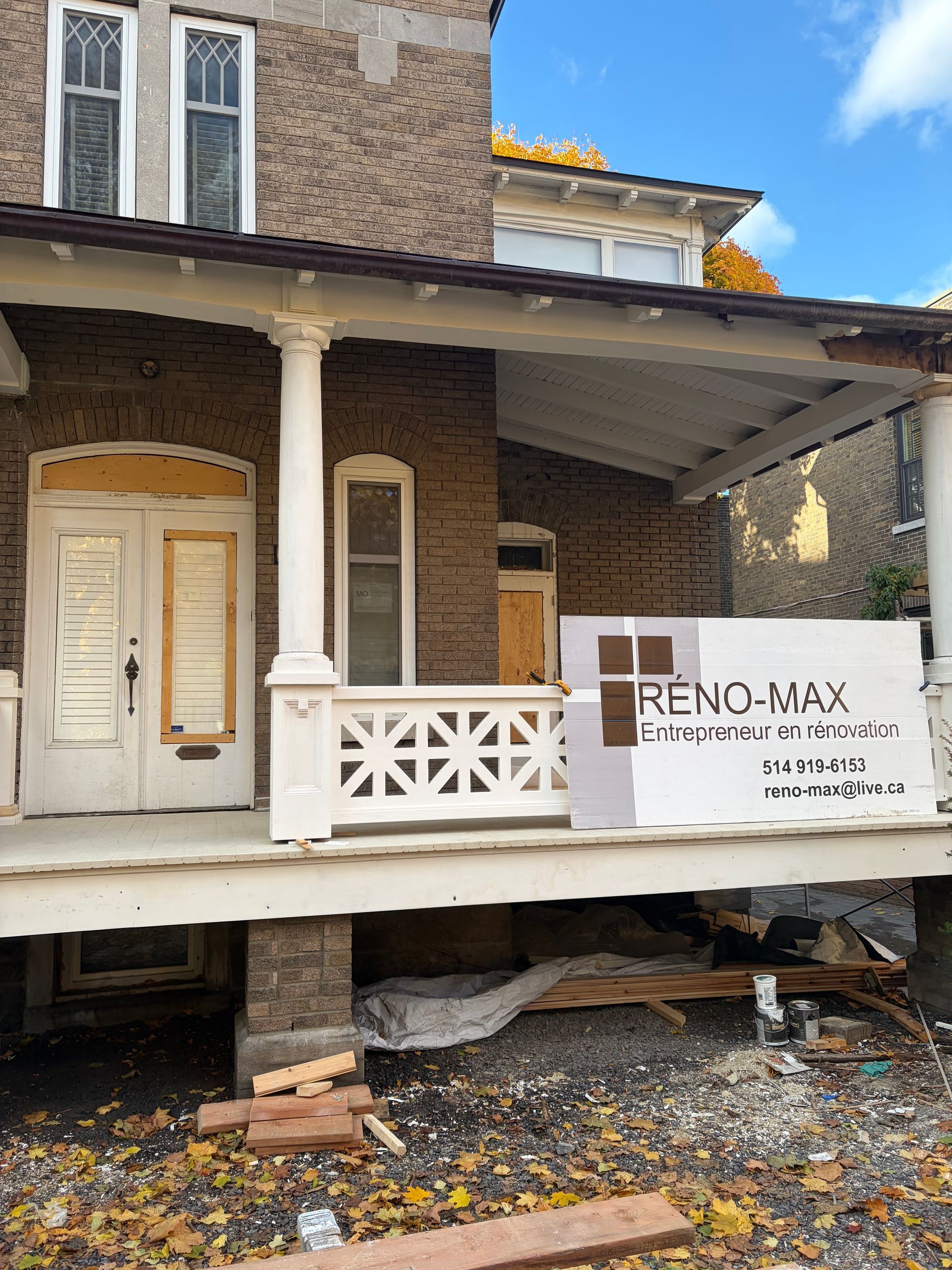 Porche endommagé sur une maison en briques avec une banderole de rénovation RE/MAX et des poutres de soutien cassées.