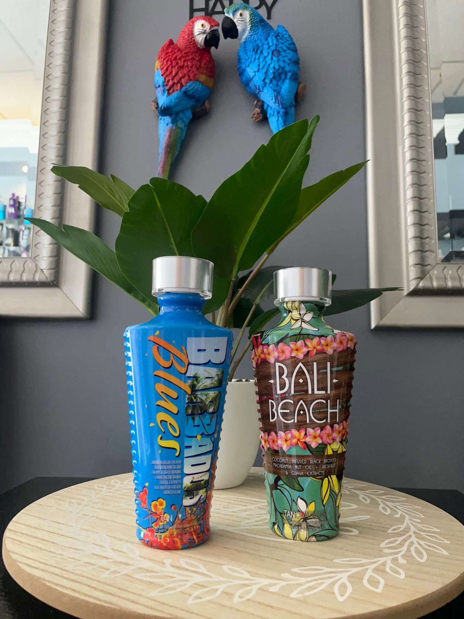 Two colorful water bottles on a round table beneath wall art of two parrots.