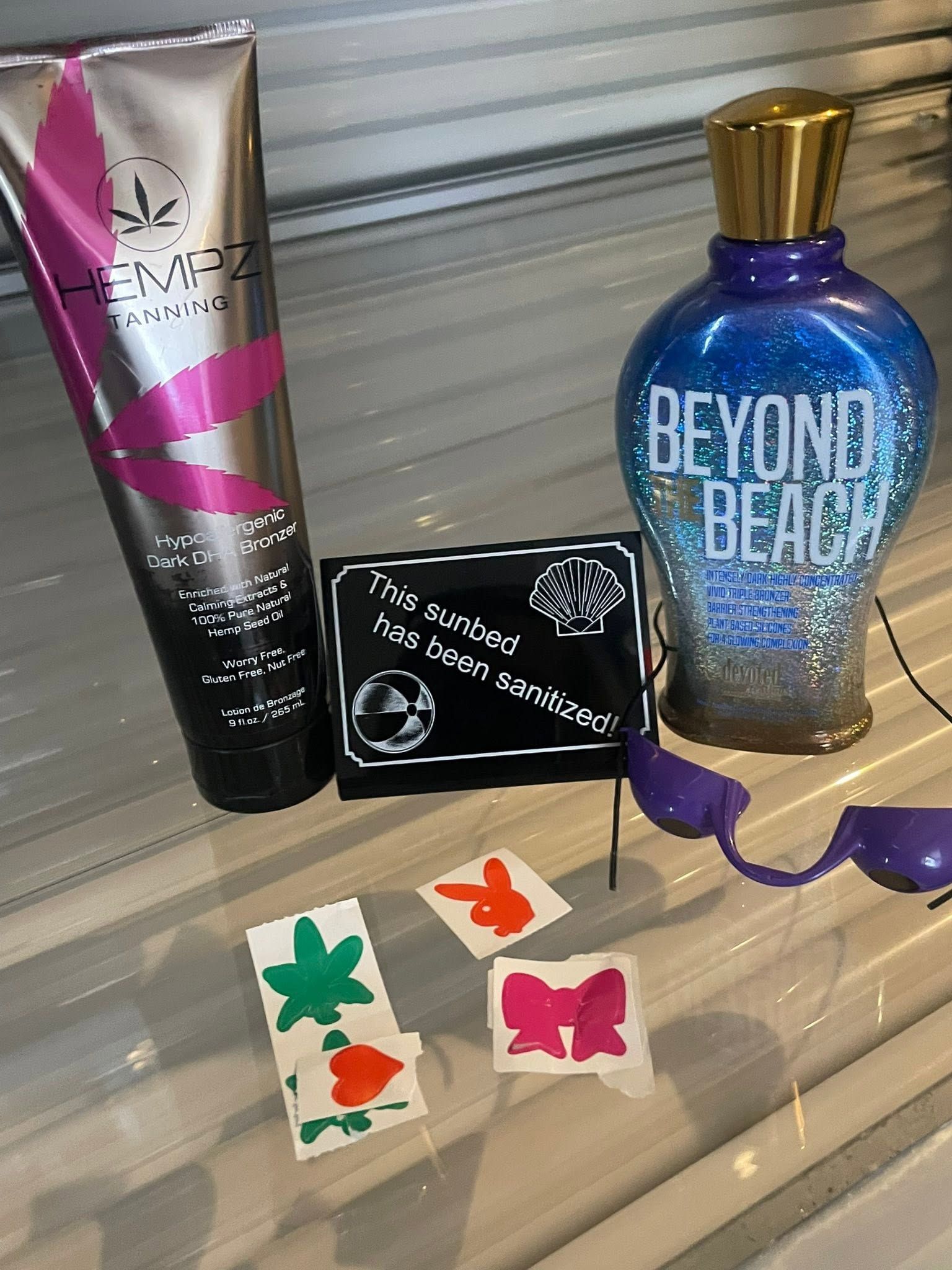 Beauty products and butterfly hair clips arranged on a shelf, with purple sunglasses and a Beyond Beach bottle.