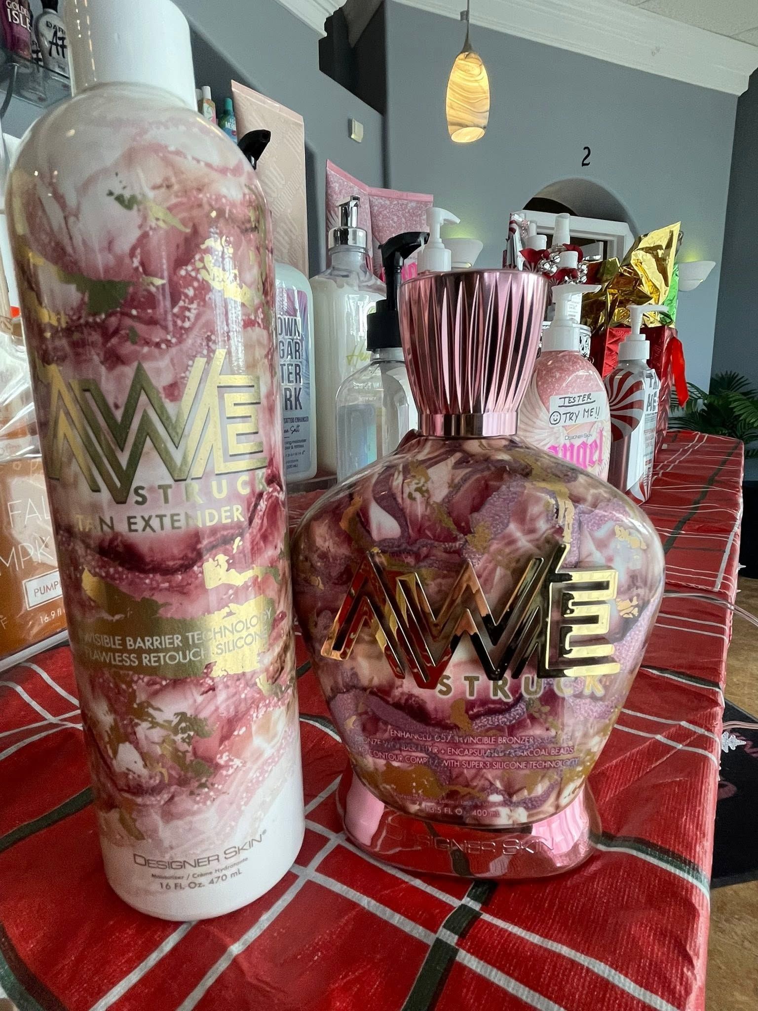 Pink and white bath and body products with floral designs on a red plaid tablecloth