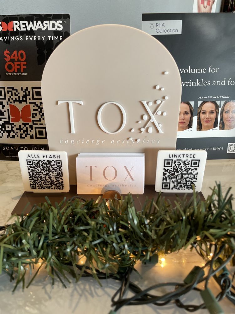 TOX skincare display with QR code stands and lit garland on a counter