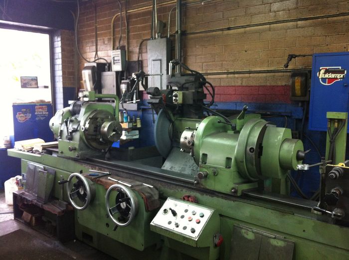 A large green machine is sitting in a room with a brick wall.