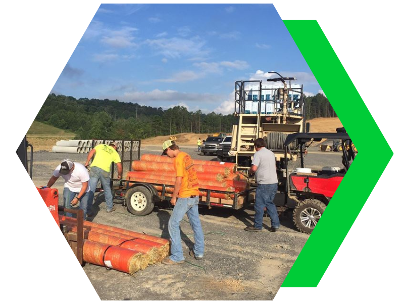 Workers loading red equipment onto a trailer at an outdoor construction site