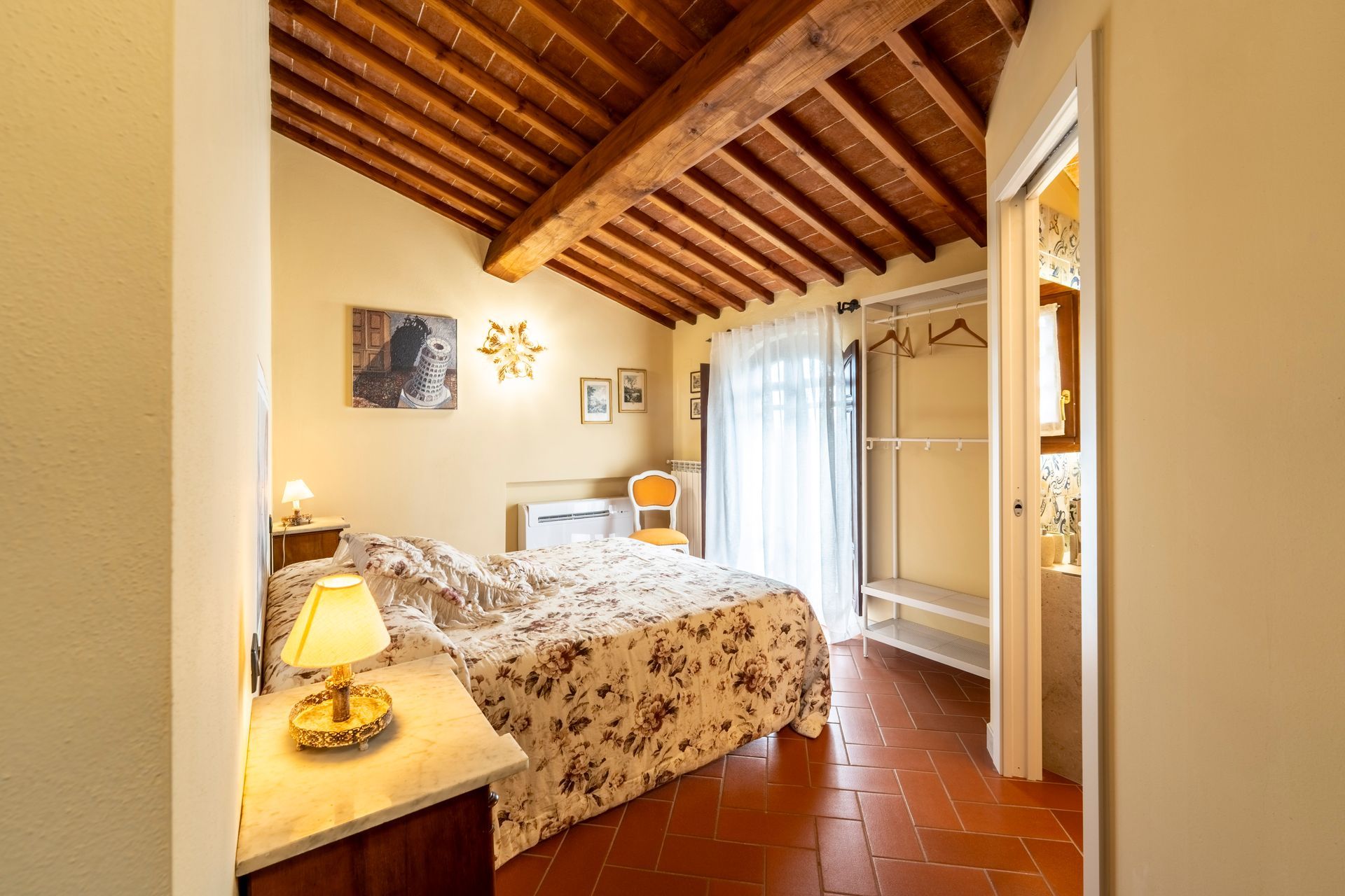Accogliente camera da letto con biancheria da letto a motivi floreali, mobili in legno e luci a parete calde.