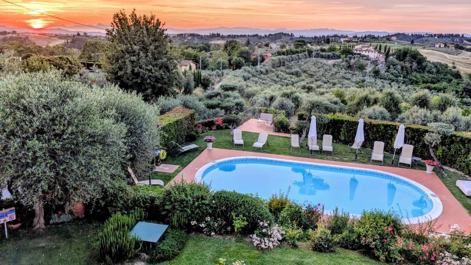 Cucina rustica con tavolo in legno, porta aperta sul giardino e calda luce del sole che filtra all'interno