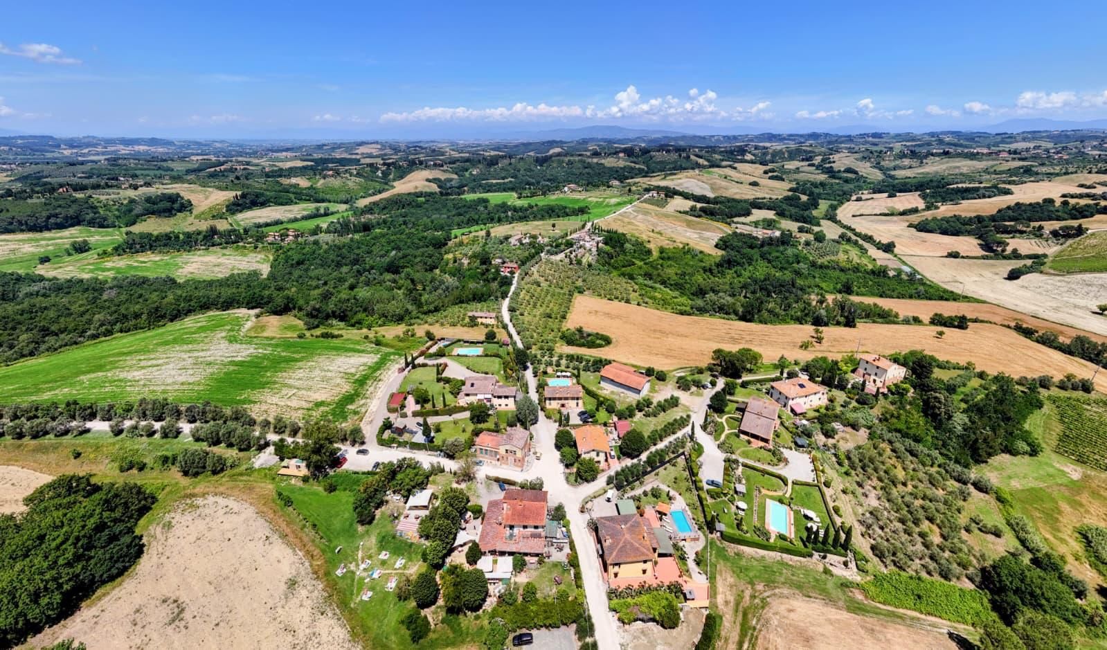 Accogliente soggiorno con camino in pietra, tende arancioni e poltrone rosse e beige.