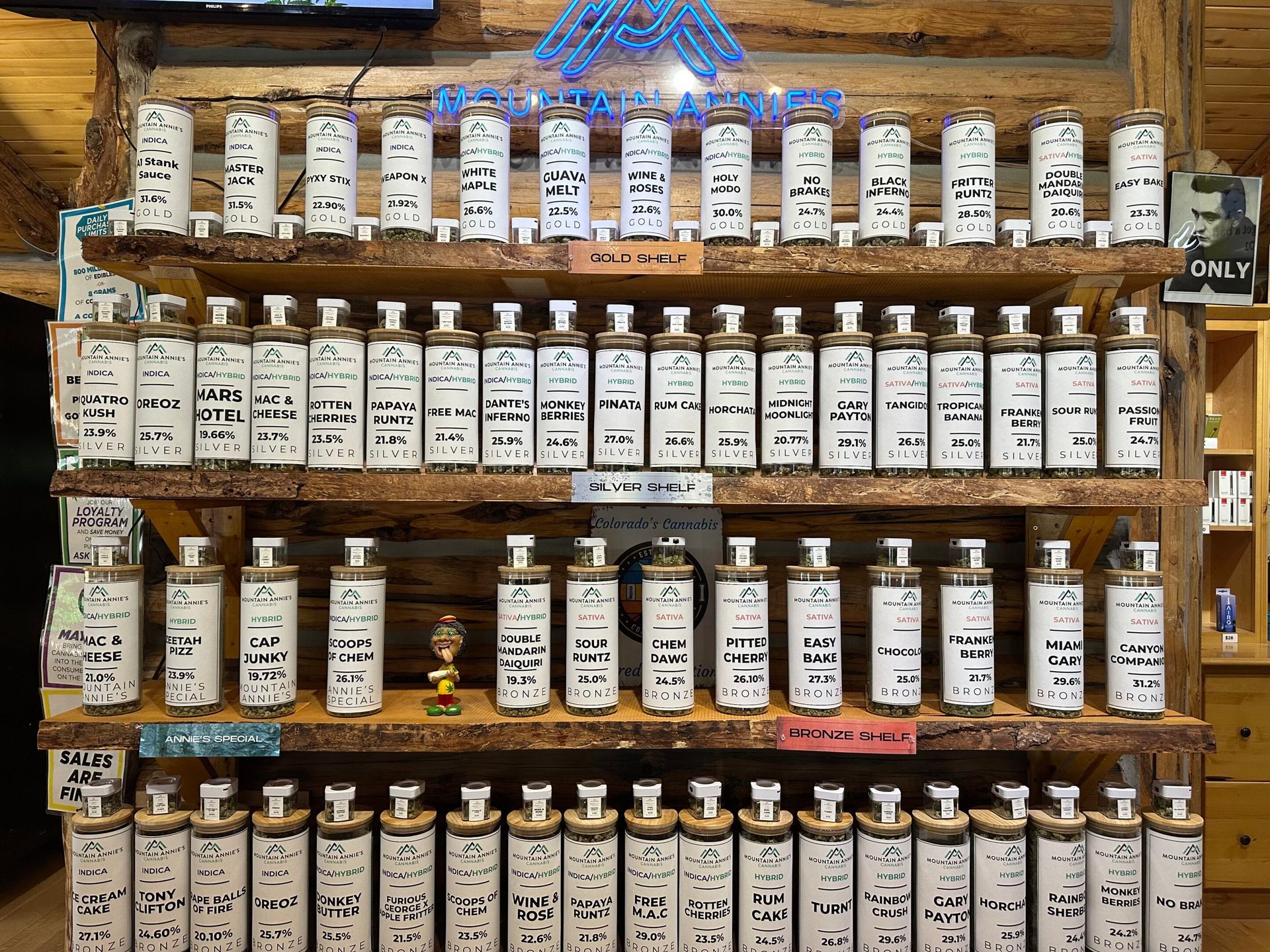 Wooden shelves lined with numerous glass jars containing various powders or spices in a store.