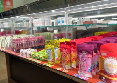 A retail shelf filled with various branded cannabis edible pouches, including Berry Blaze and citrus-flavored products.