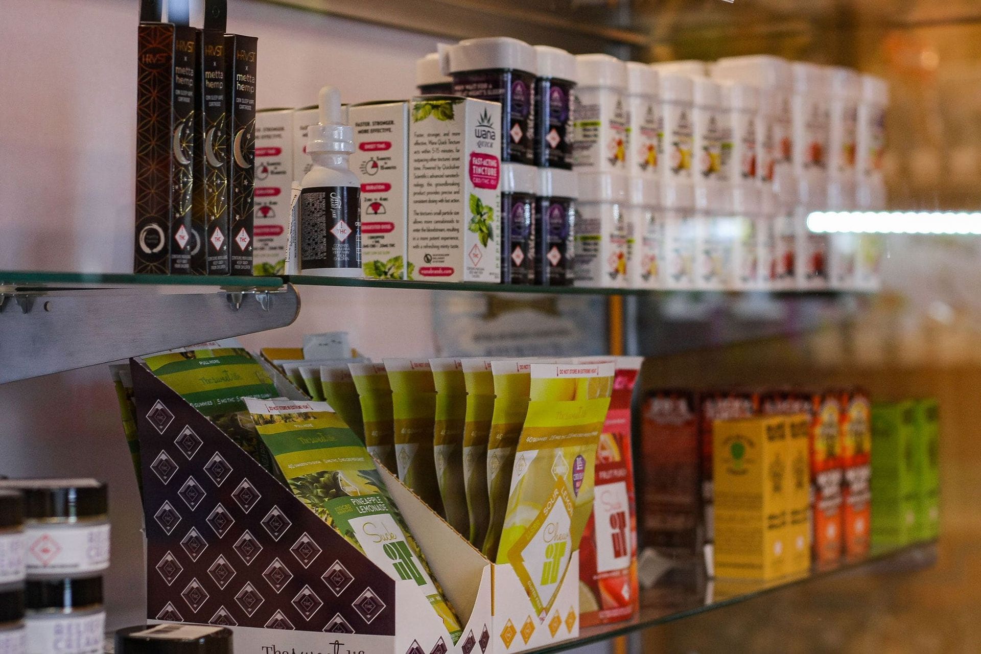 Shelves in a store display various bottled supplements, herbal products, and boxed tea in a retail setting.