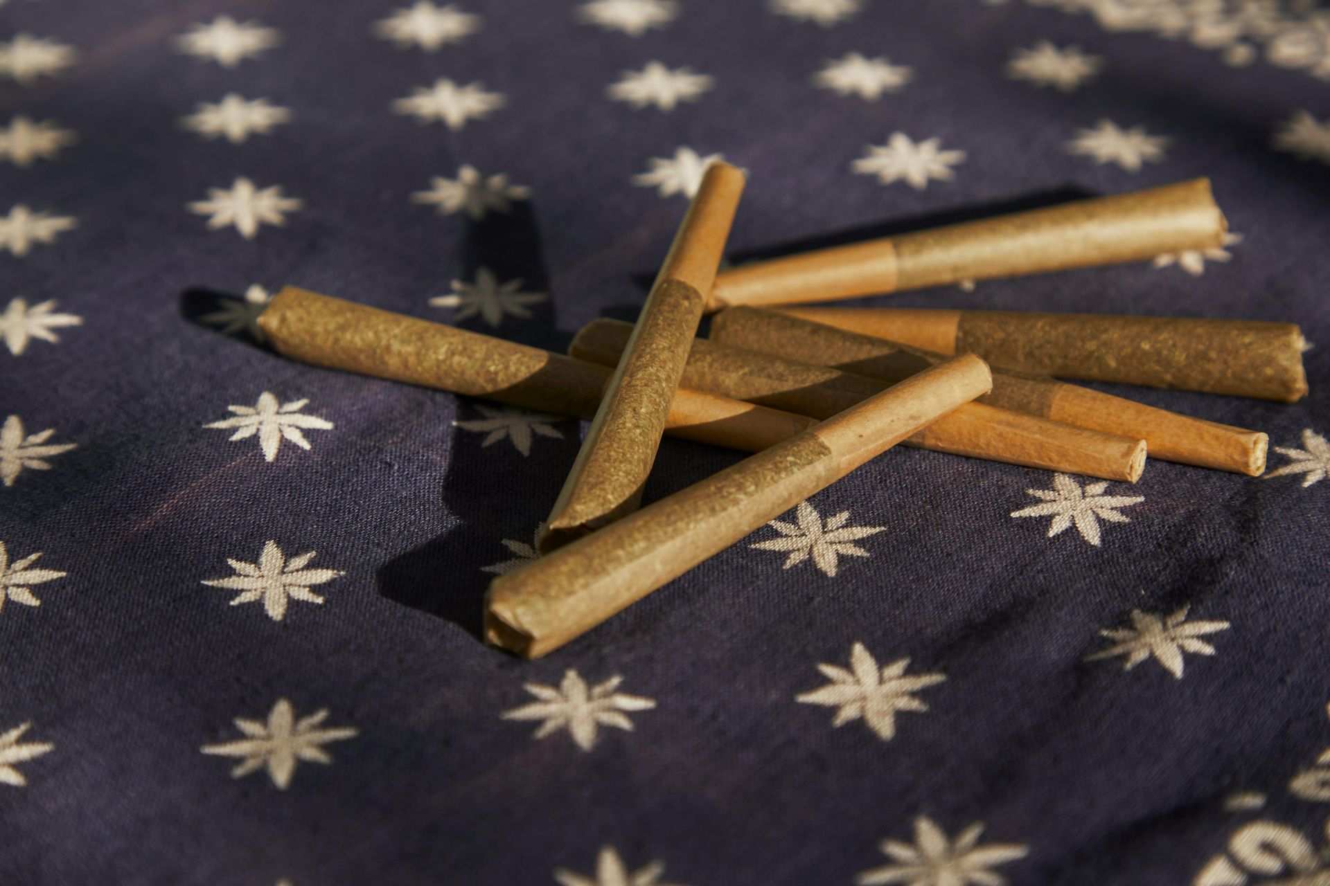 Several hand-rolled cigars are clustered together on a dark blue cloth patterned with small white stars.