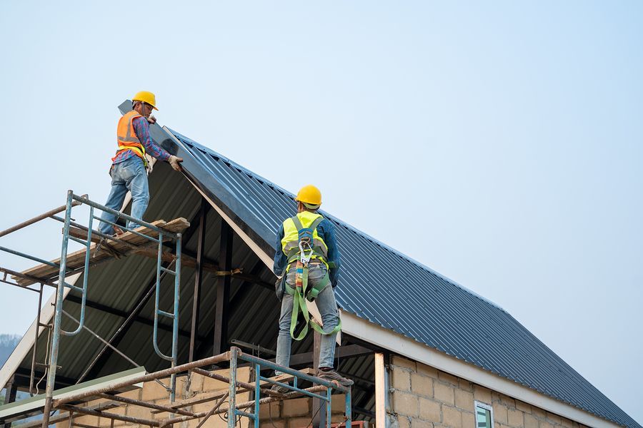 a couple of men standing on top of a metal roof