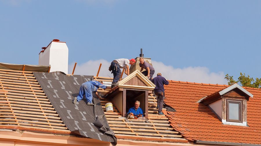 a group of men working on the roof of a house