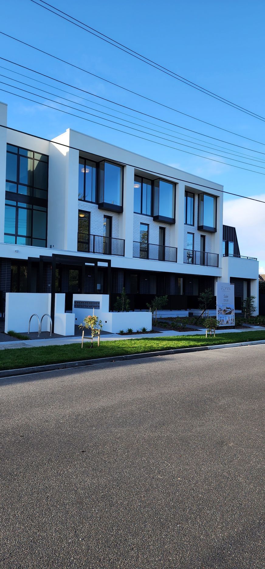 A large white building with a lot of windows is sitting on the side of the road.