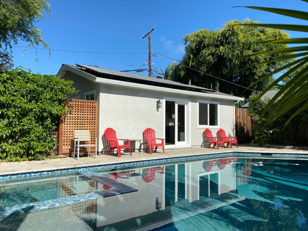 A house with a pool and red chairs in front of it
