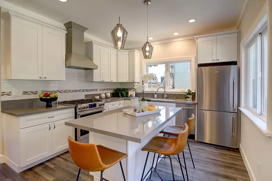 A kitchen with white cabinets , stainless steel appliances , and a large island.