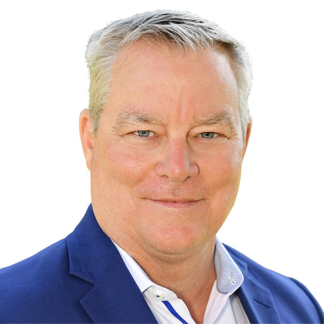 A man in a blue suit and white shirt is smiling for the camera.