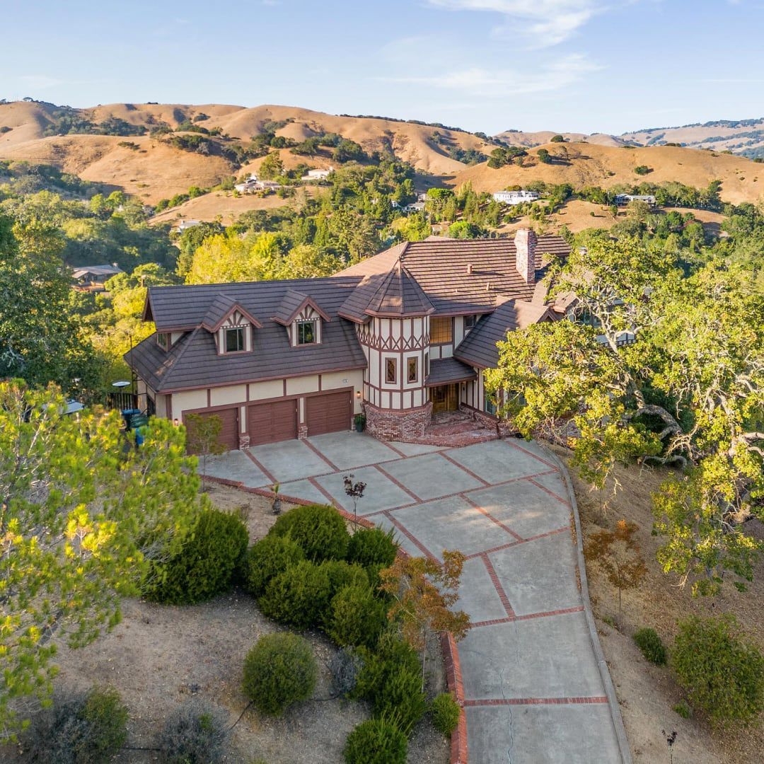 An aerial view of a large house surrounded by trees and mountains.