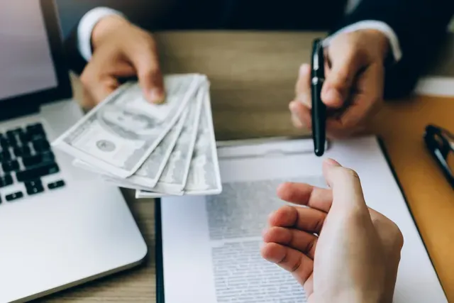 A person is handing a stack of money to another person.