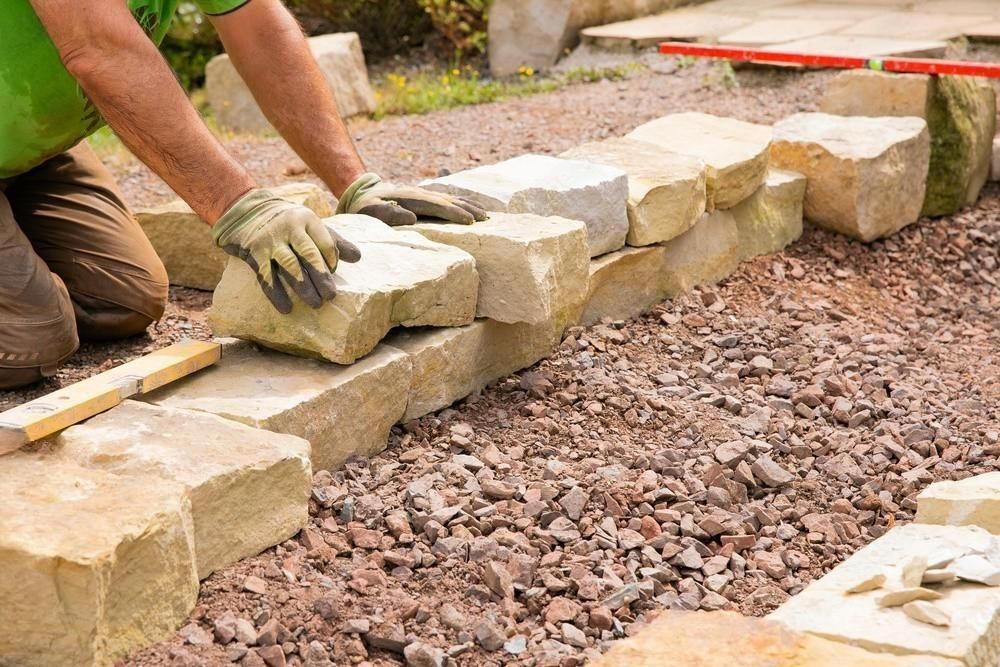 a man is kneeling down to build a stone wall .