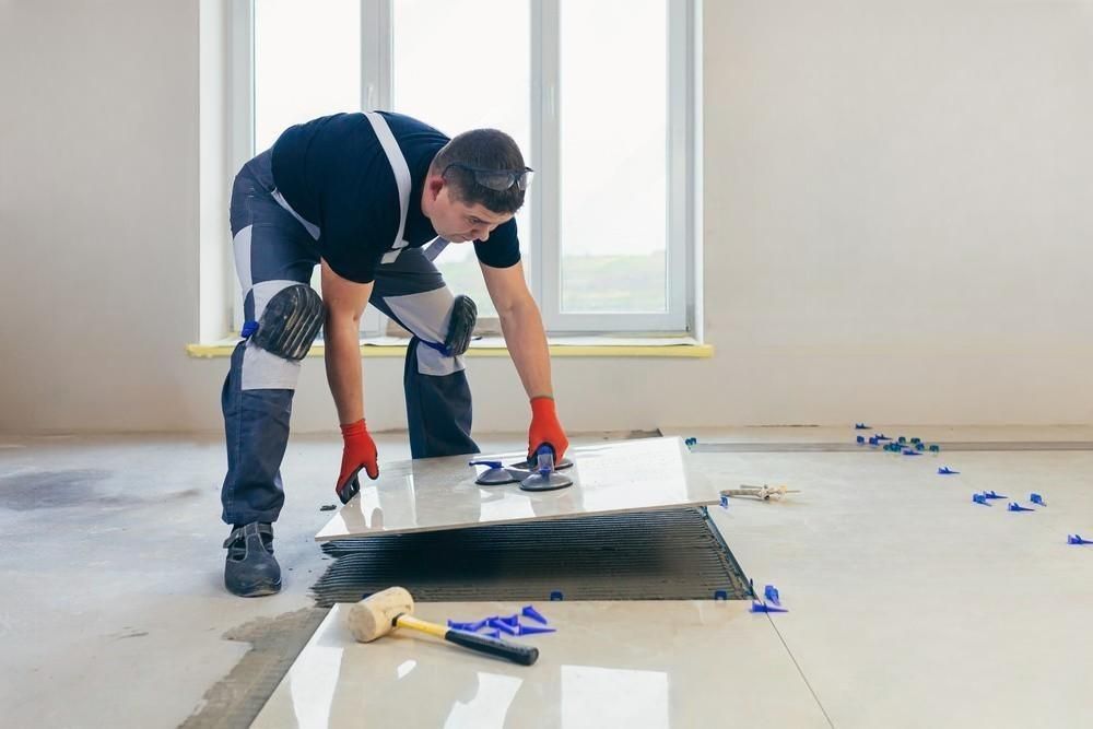 a man is laying a tile floor in a room .
